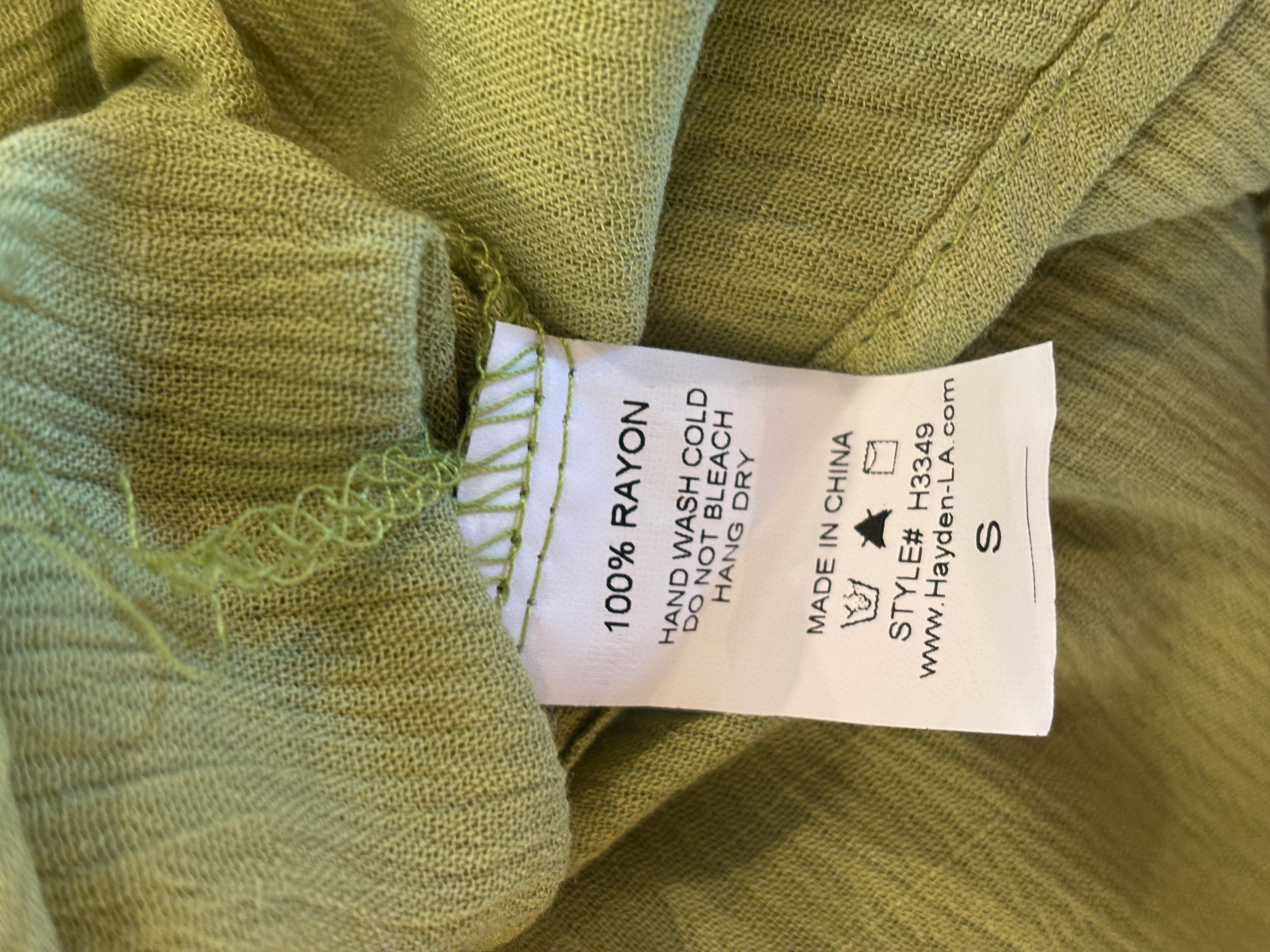 Care label showing 100% rayon, hand wash cold, hang dry on Hayden LA green dress