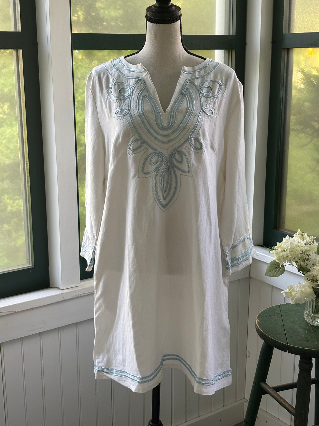 Les Canebiers white embroidered tunic dress on mannequin, split V-neckline with sky blue scrolling medallion embroidery at chest