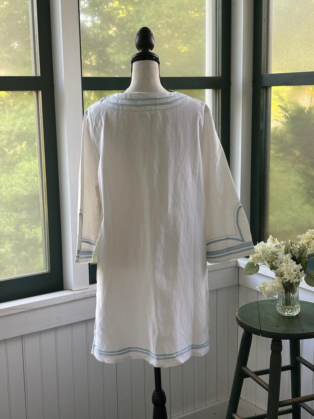 Back view of Les Canebiers white embroidered tunic dress on mannequin showing clean A-line silhouette and embroidered hem trim