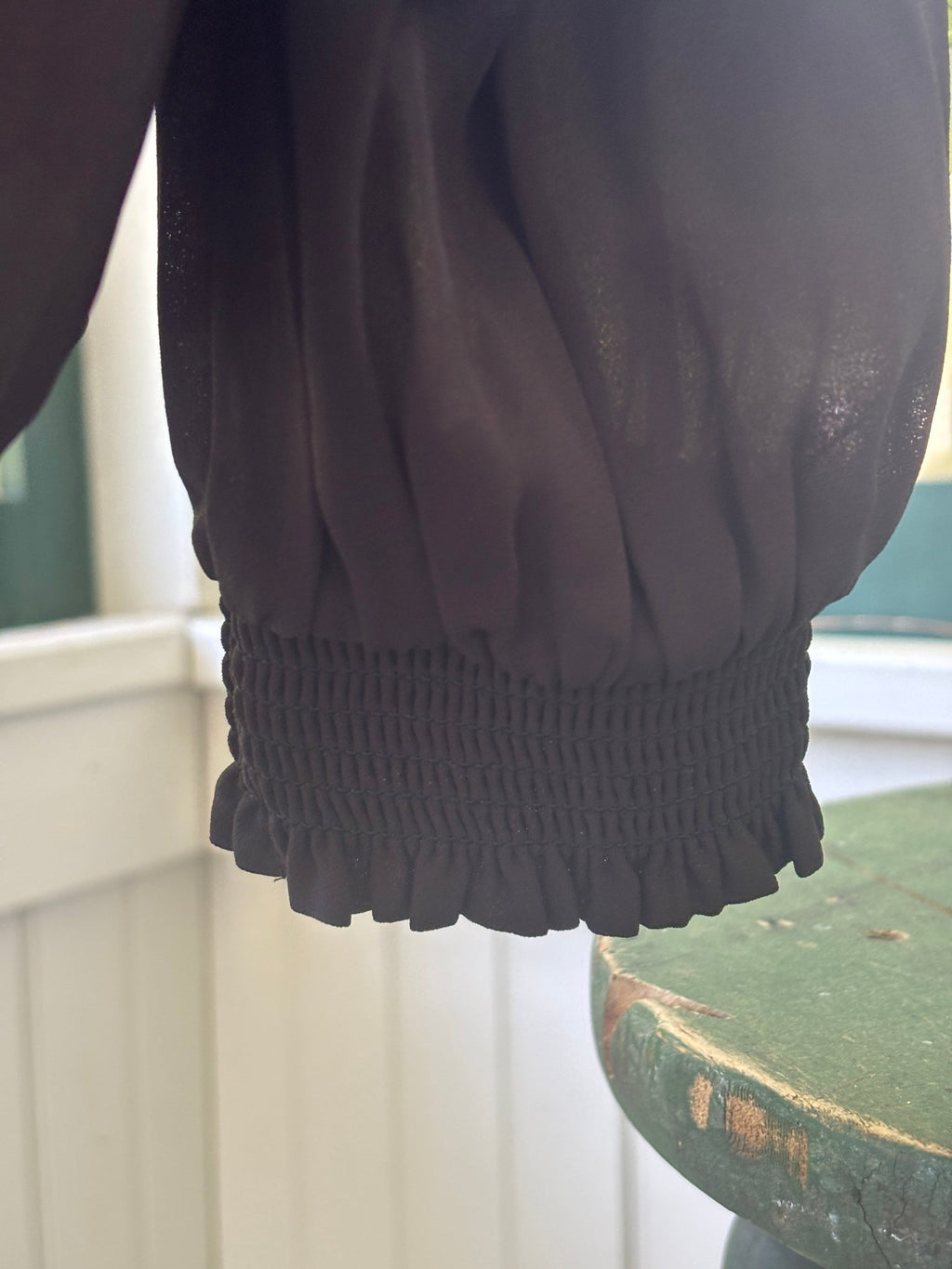 Close-up of smocked ruffle cuff detail on long sleeve of Ann Taylor black chiffon blouse