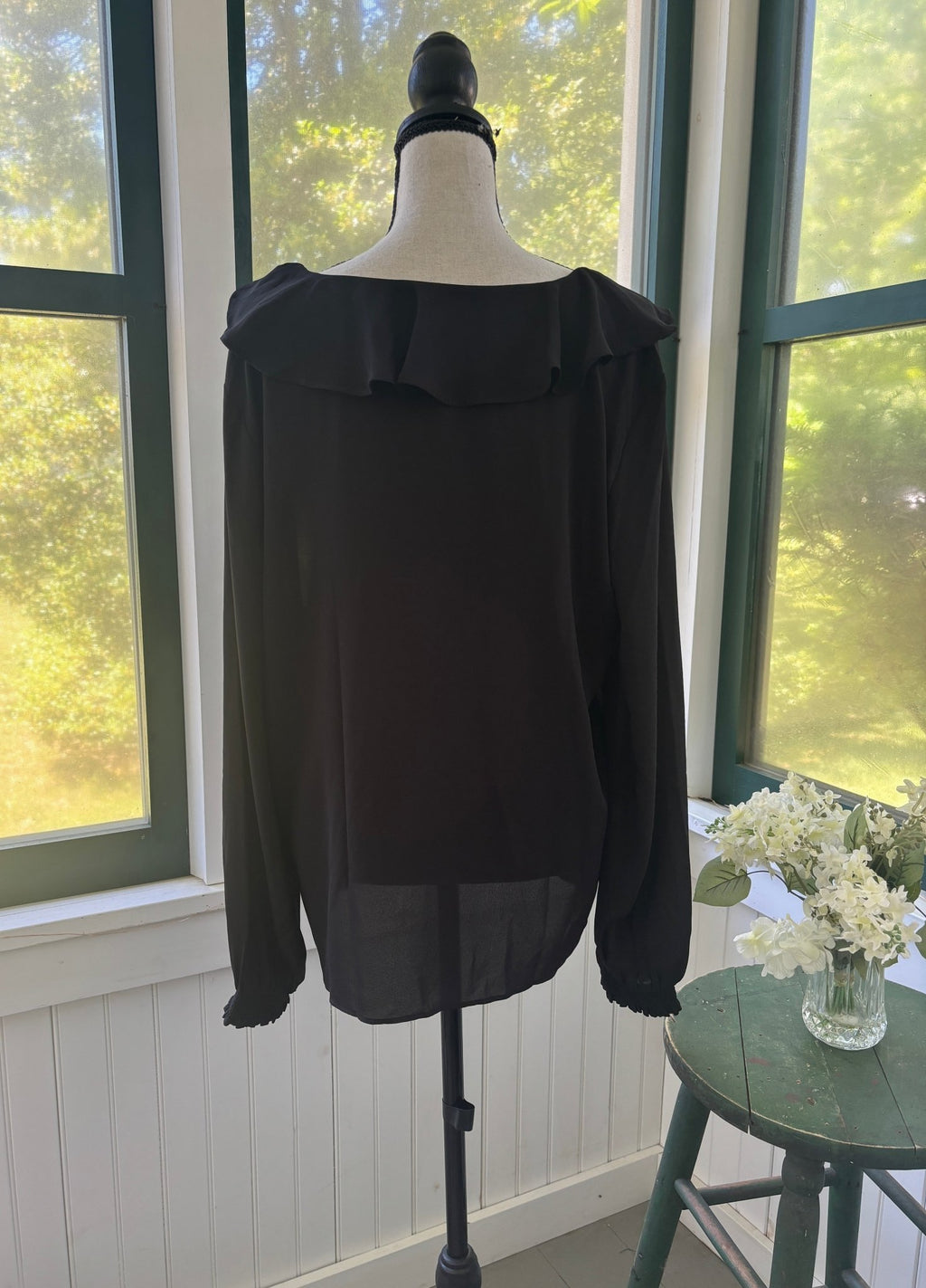 Back view of Ann Taylor black ruffle blouse on mannequin showing relaxed fluid silhouette