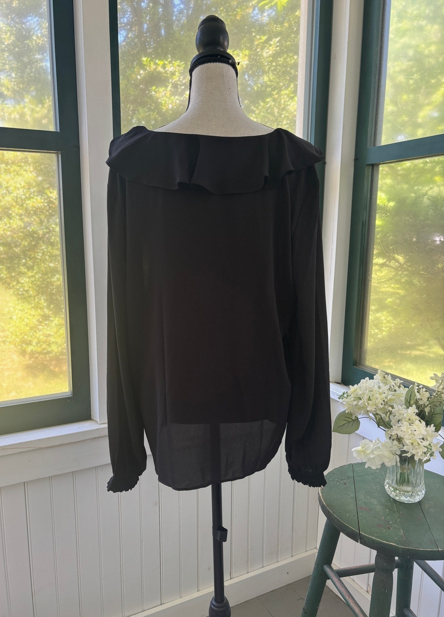 Back view of Ann Taylor black ruffle blouse on mannequin showing relaxed fluid silhouette