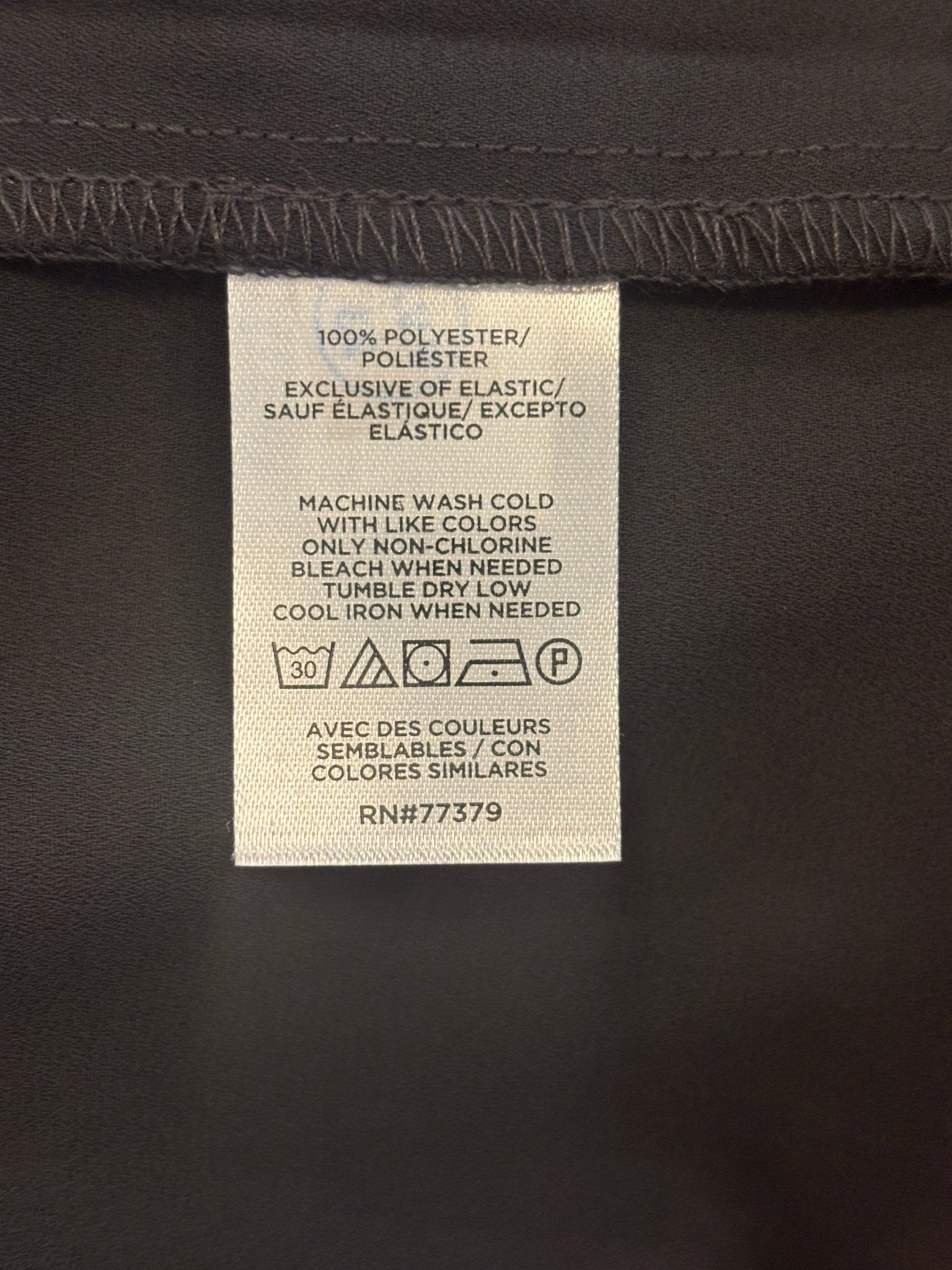 Care label showing 100% Polyester machine wash cold for Ann Taylor black ruffle blouse