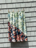 Anthropologie LyreBird Ivory Comb floral colorblock midi skirt front view showing diagonal panel with sage mint botanical and navy floral print, size XL NWT