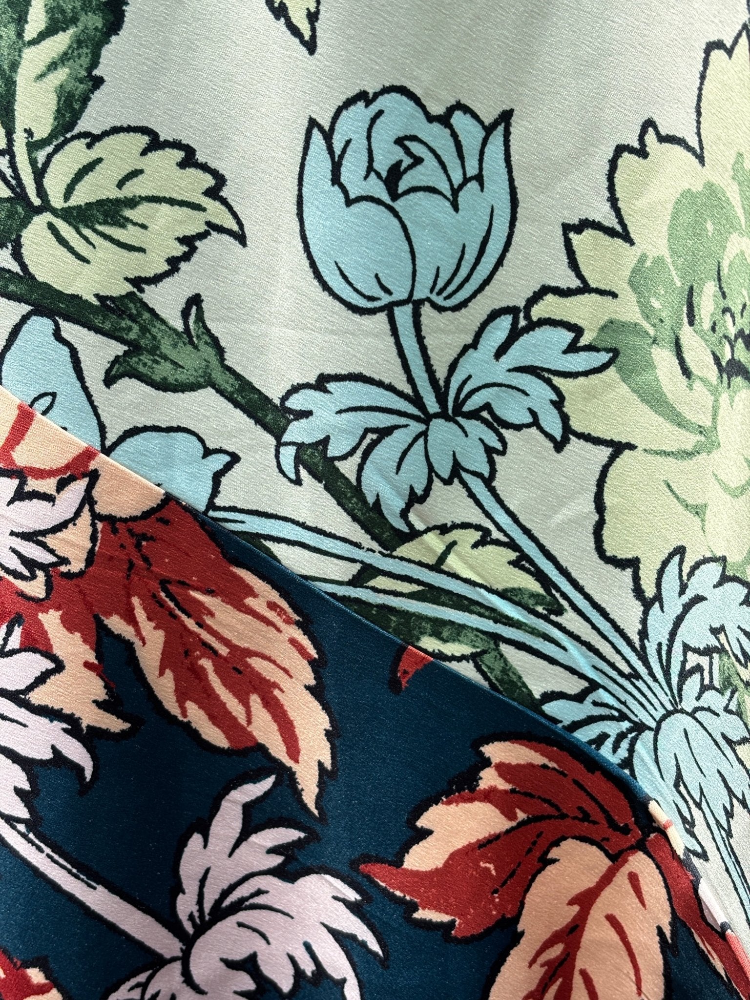 Close-up of diagonal colorblock panel detail showing sage mint floral on cream meeting navy ground with russet and blush blooms
