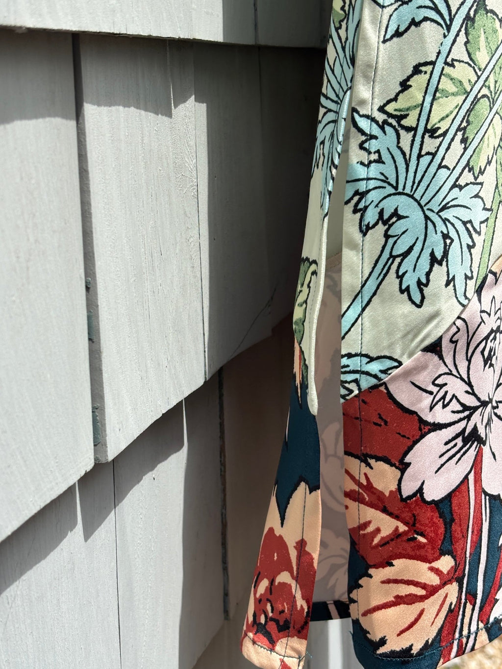 Side view detail showing the diagonal colorblock seam and silky drape of Anthropologie LyreBird skirt