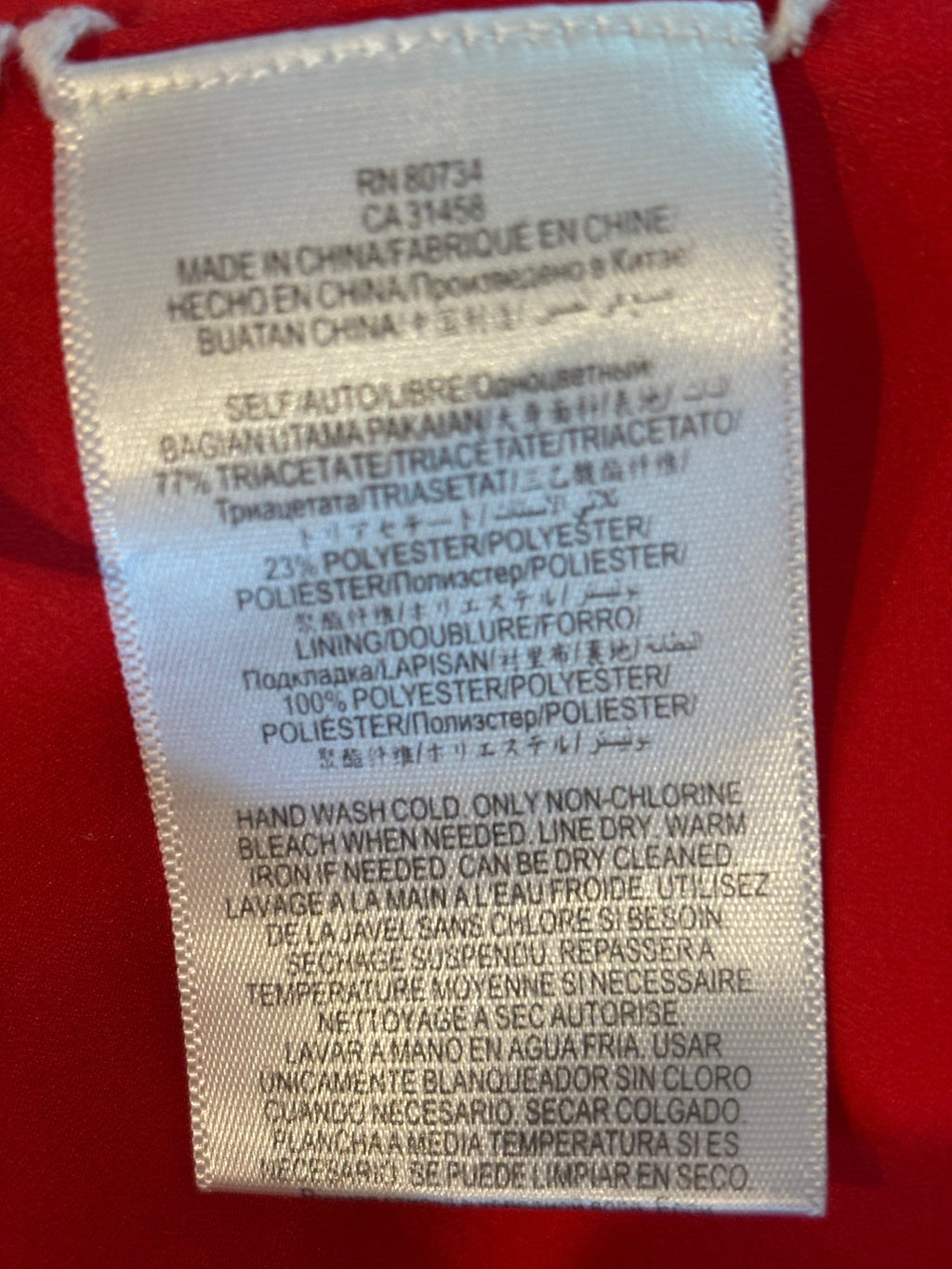 Care label showing 77% triacetate 23% polyester shell, 100% polyester lining, hand wash cold instructions