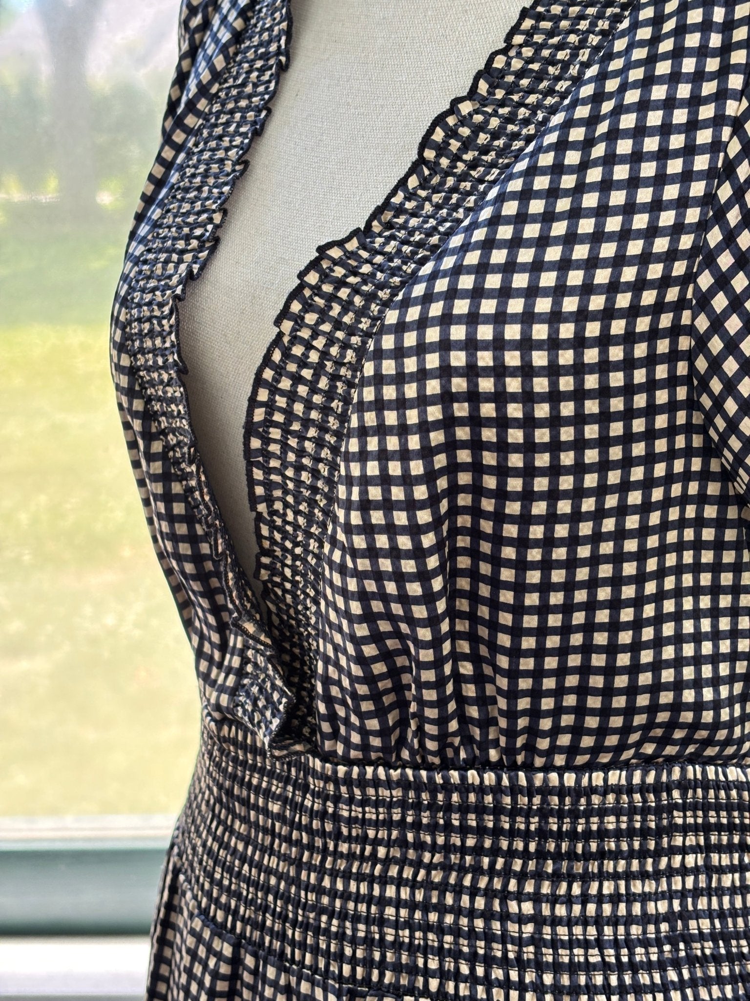 Close-up of ruffled V-neckline and smocked empire waist on BCBG Max Azria silk gingham dress