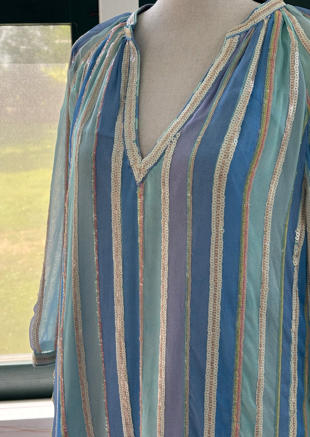 Close-up of V-neckline with sequin trim border on Bella Tu sky blue stripe tunic dress