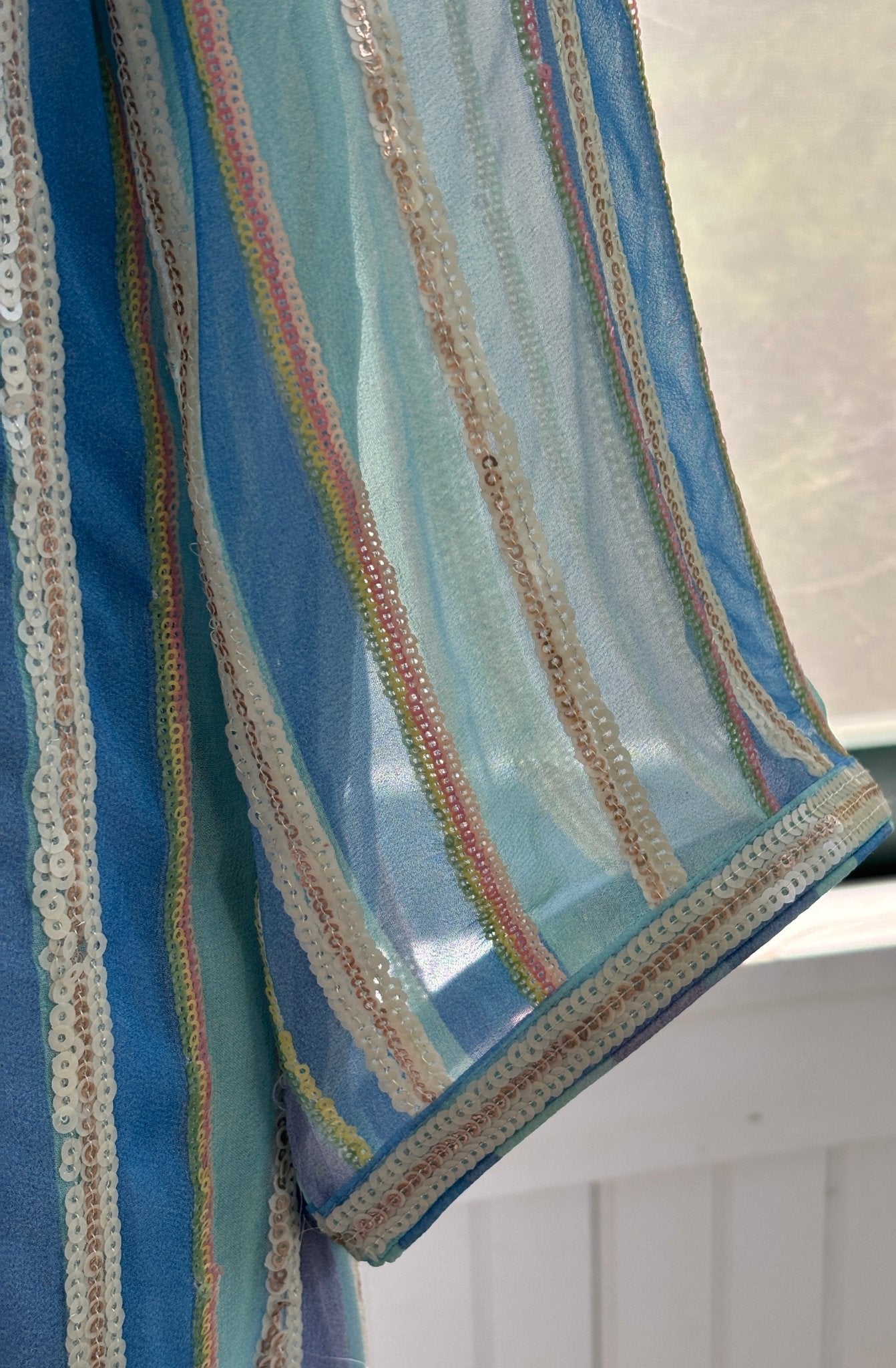 Close-up of sleeve hem showing sequin stripe detail in cream, gold, blush and sage on Bella Tu tunic dress