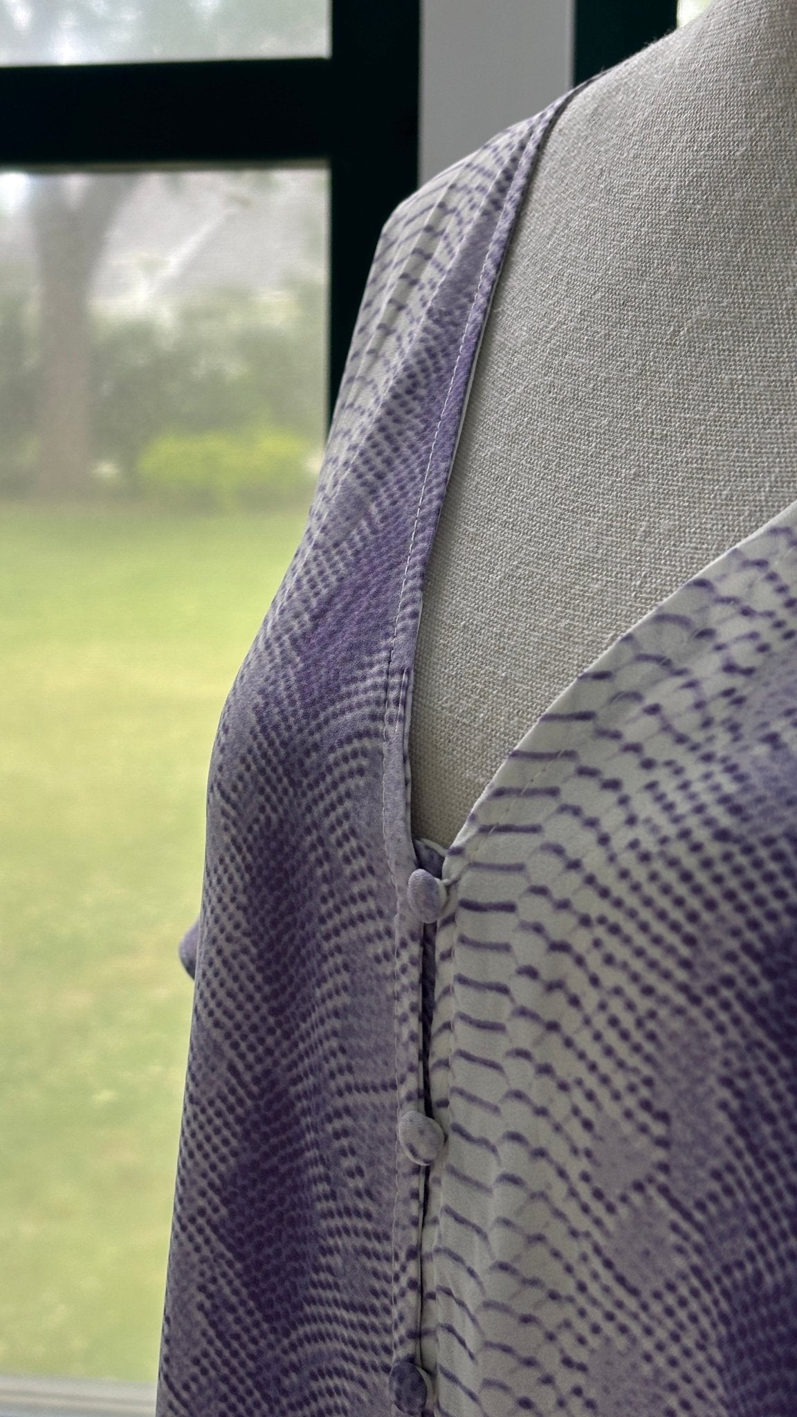 Close-up of fabric-covered button detail and V-neckline on BuddyLove Hailey Haze lavender snake print mini dress