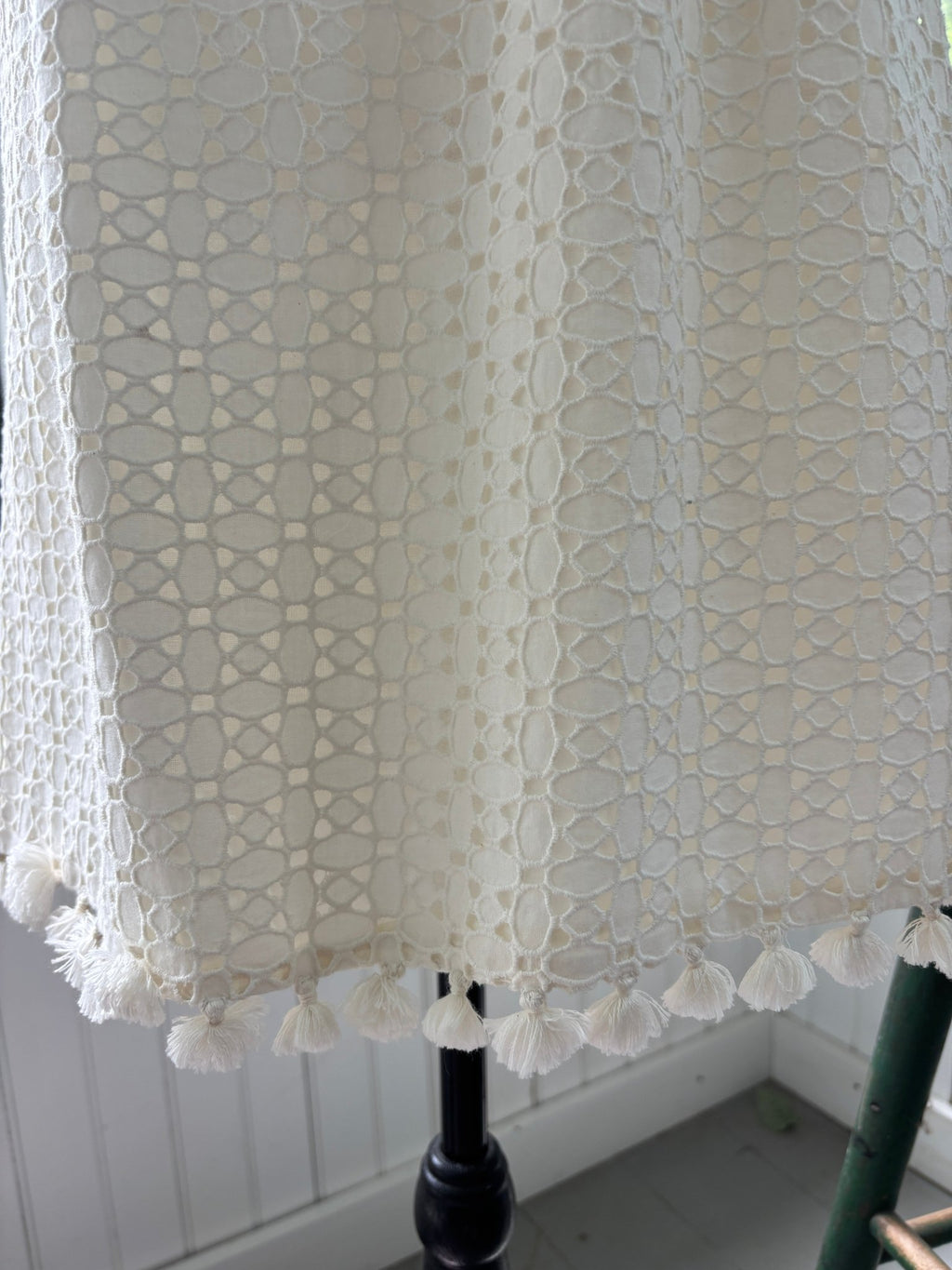 Close-up of tassel fringe hem on Calypso St. Barth white crochet lace dress