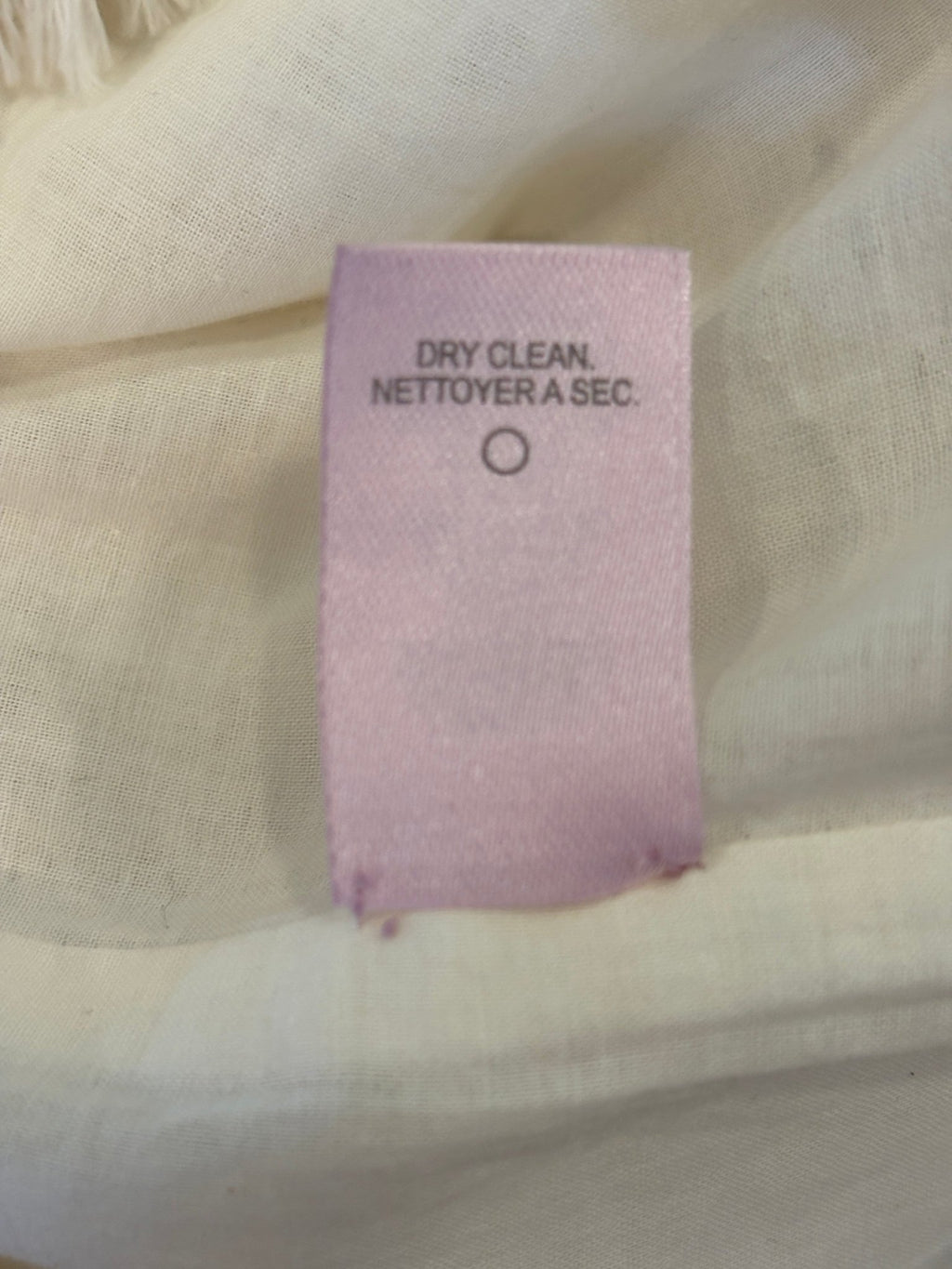 Care label showing dry clean only for Calypso St. Barth white crochet dress