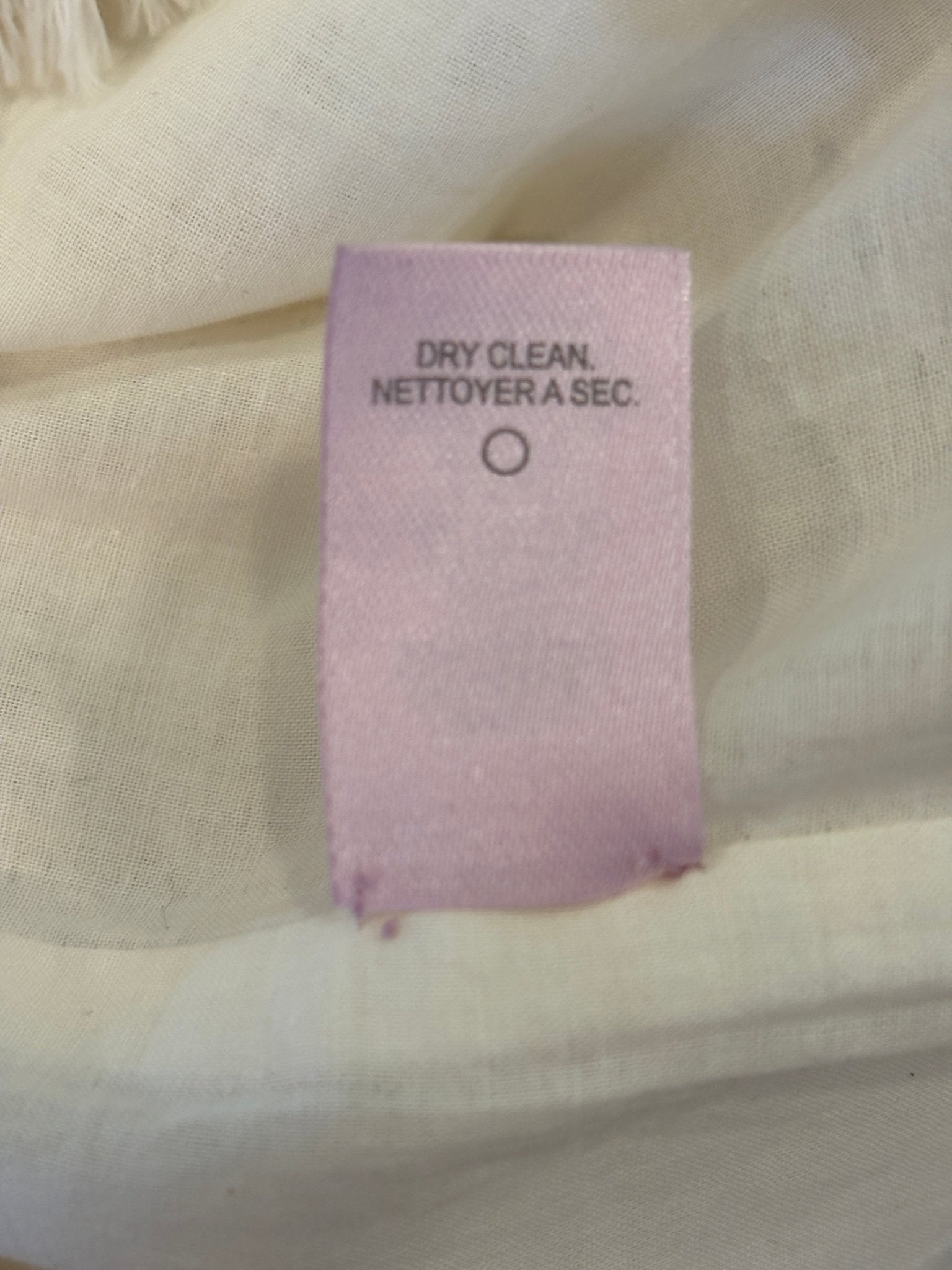 Care label showing dry clean only for Calypso St. Barth white crochet dress