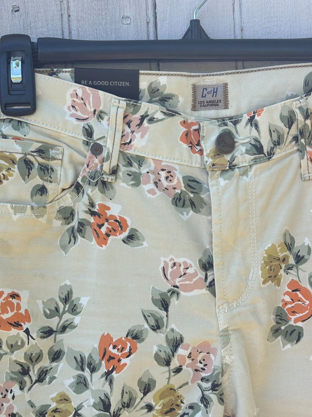 Close-up of waistband showing CofH Los Angeles California leather patch, double button closure, and floral print detail