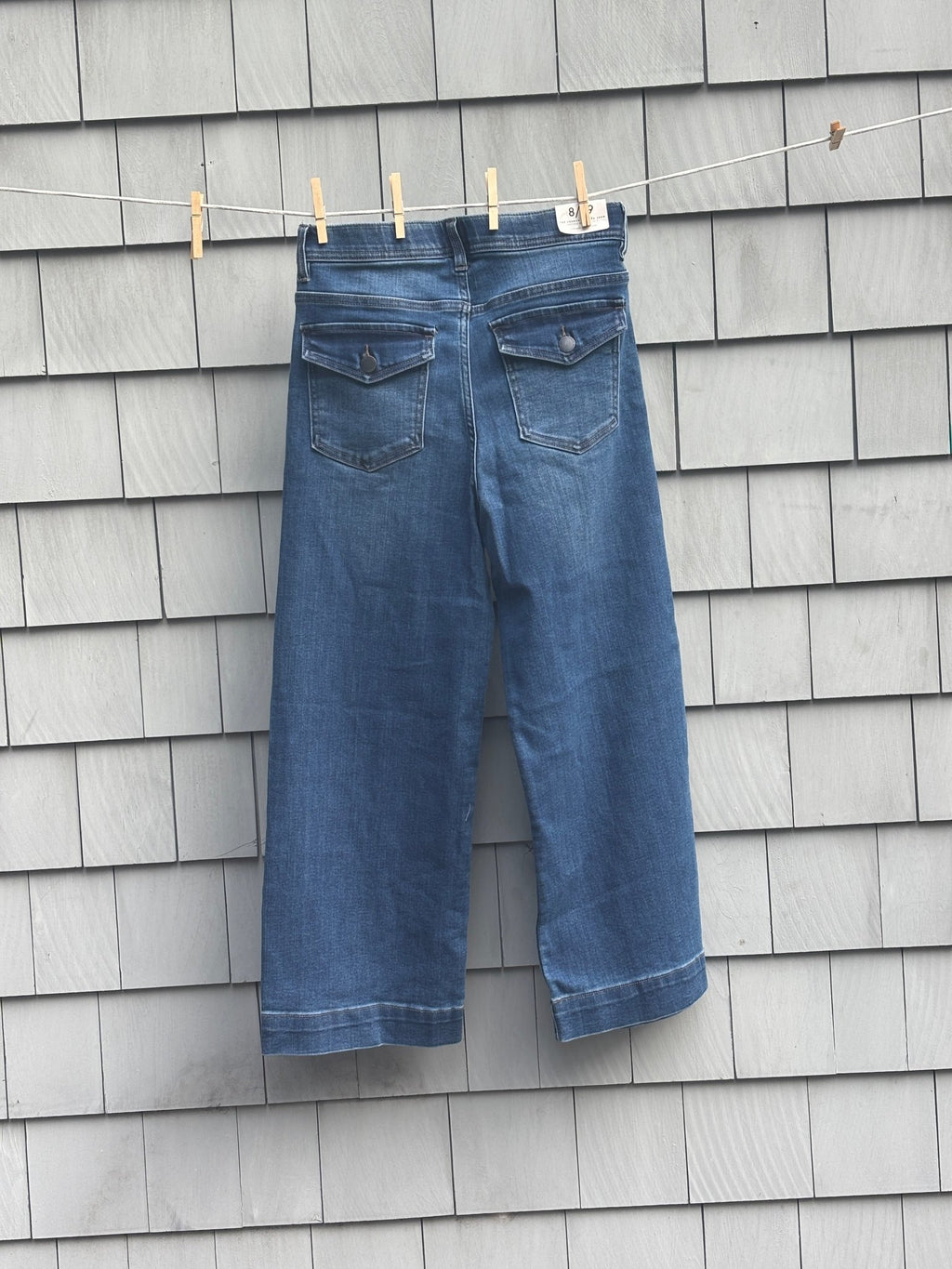 Curve Appeal wide leg crop jeans, back view showing flap pockets, hanging on clothesline
