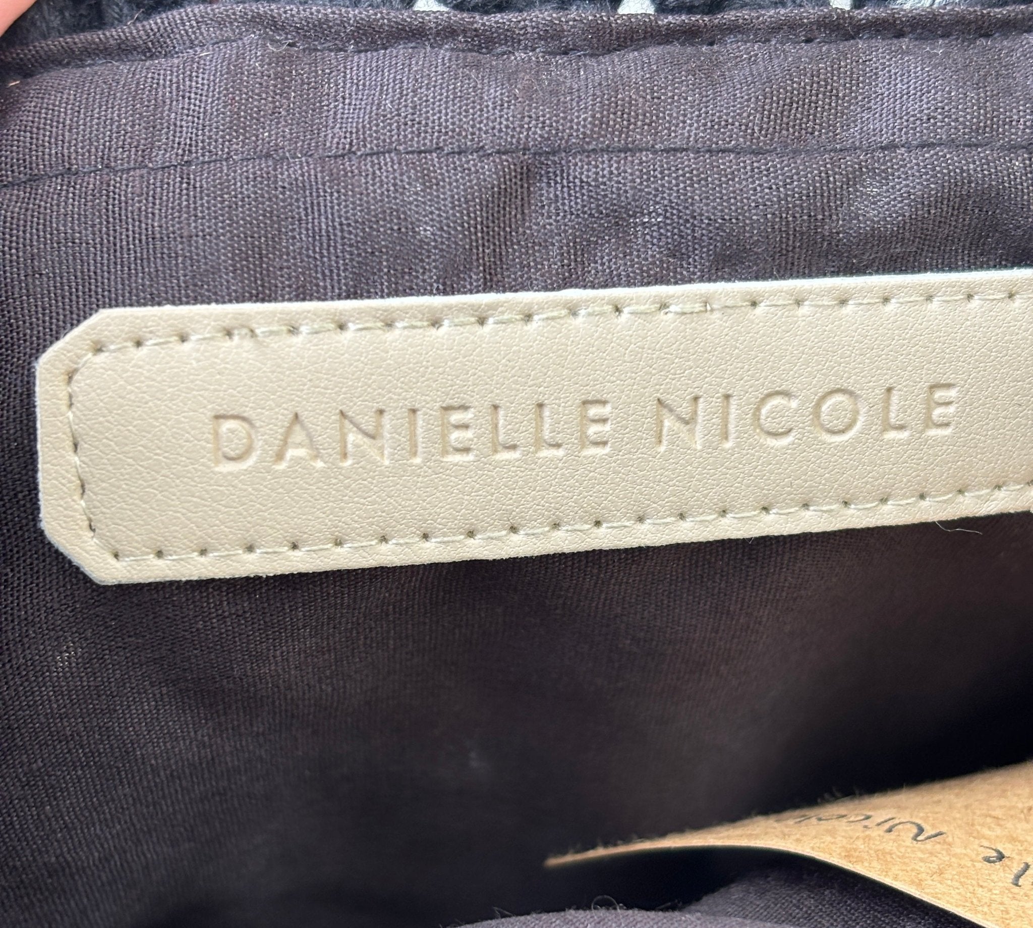 Danielle Nicole embossed leather interior label inside black macramé fringe tote bag