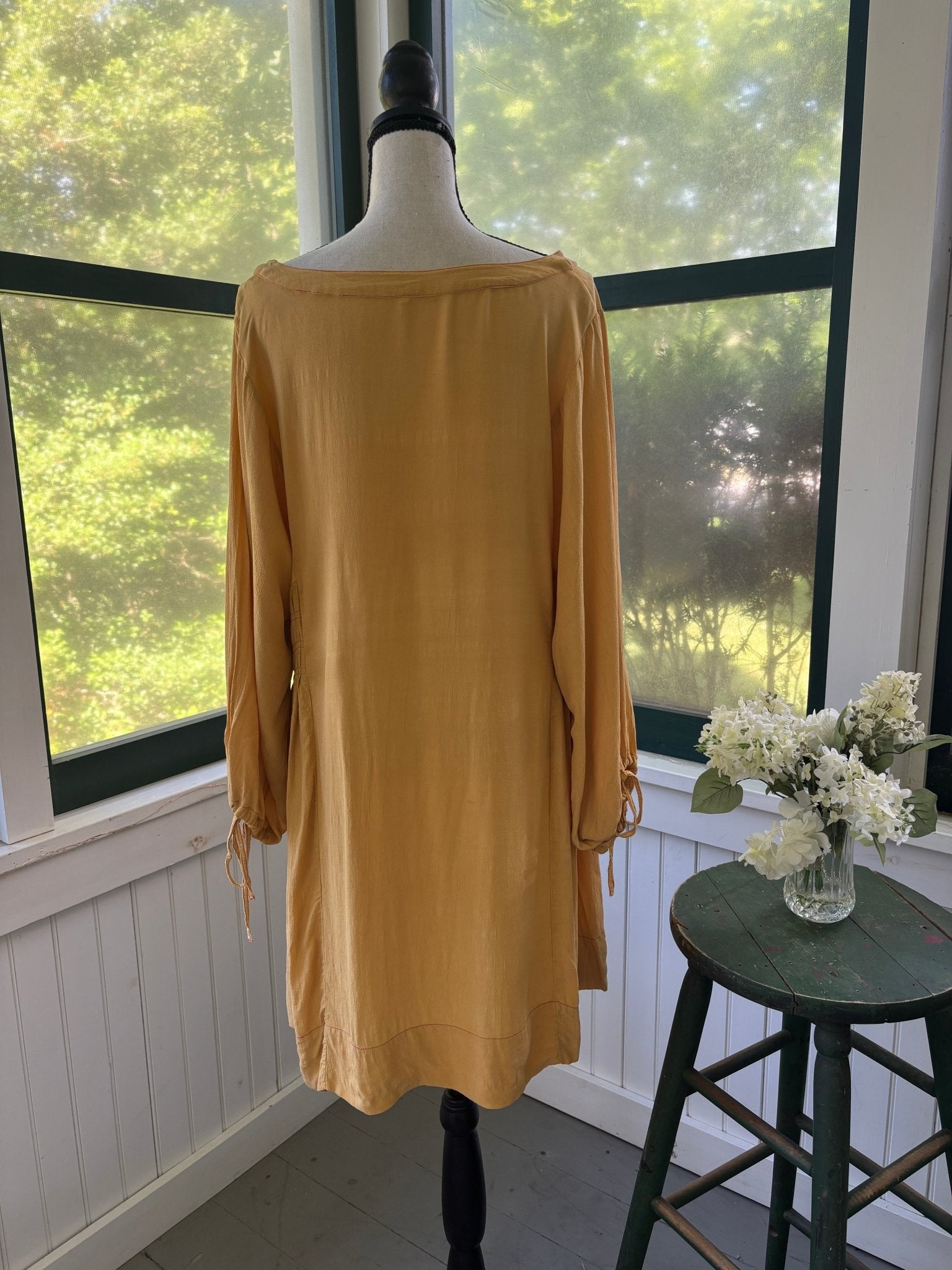 Back view of Free People Honey Honey marigold mini dress showing long sleeves with ruched tie cuffs and cinched side panels