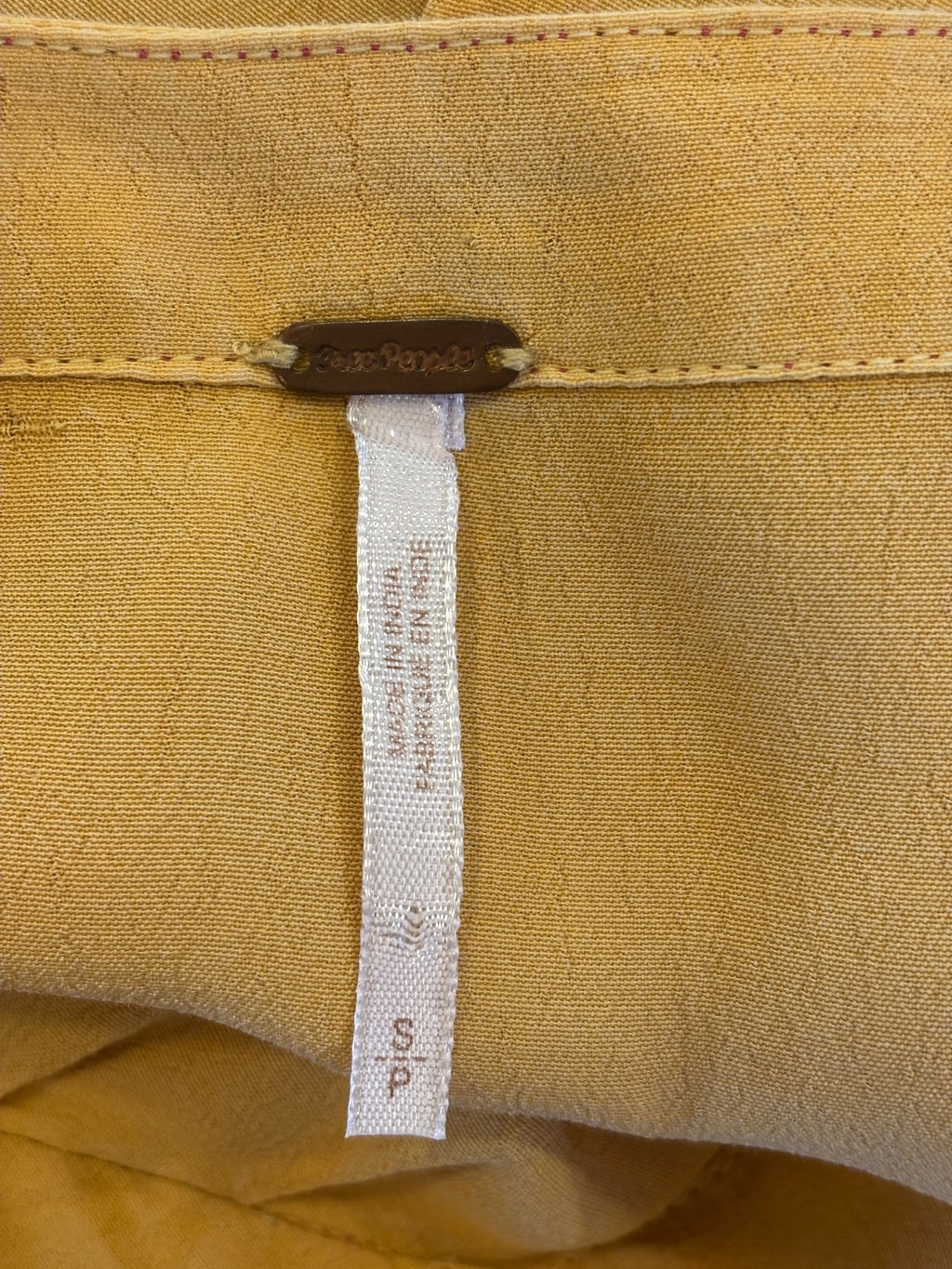 Interior waistband showing Free People brand hardware tag and size S label with care instructions