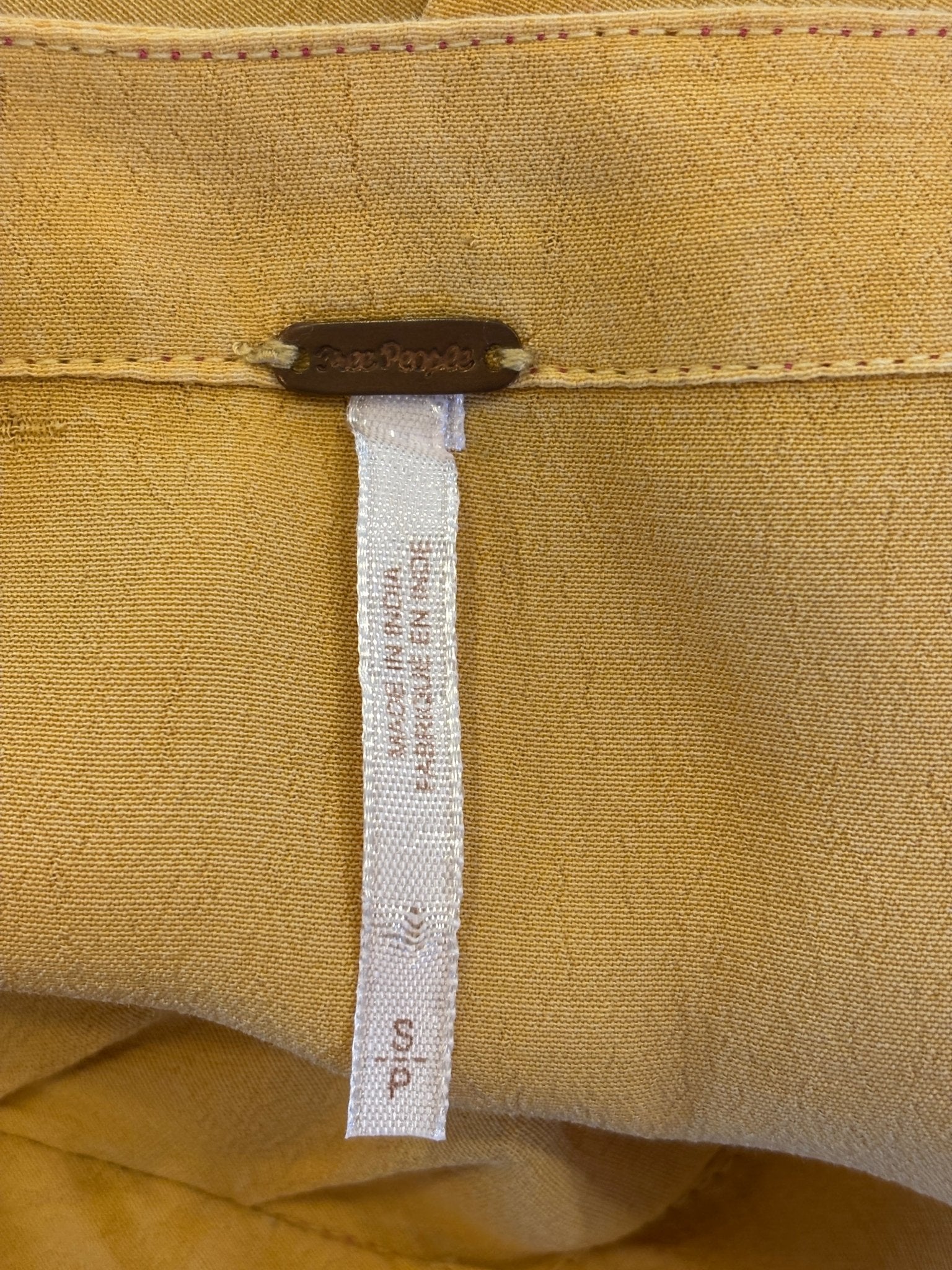 Interior waistband showing Free People brand hardware tag and size S label with care instructions
