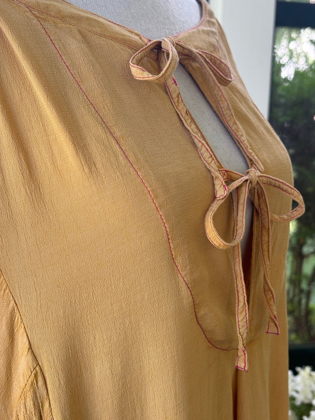 Close-up of double-tie keyhole neckline and contrast pink magenta topstitching detail