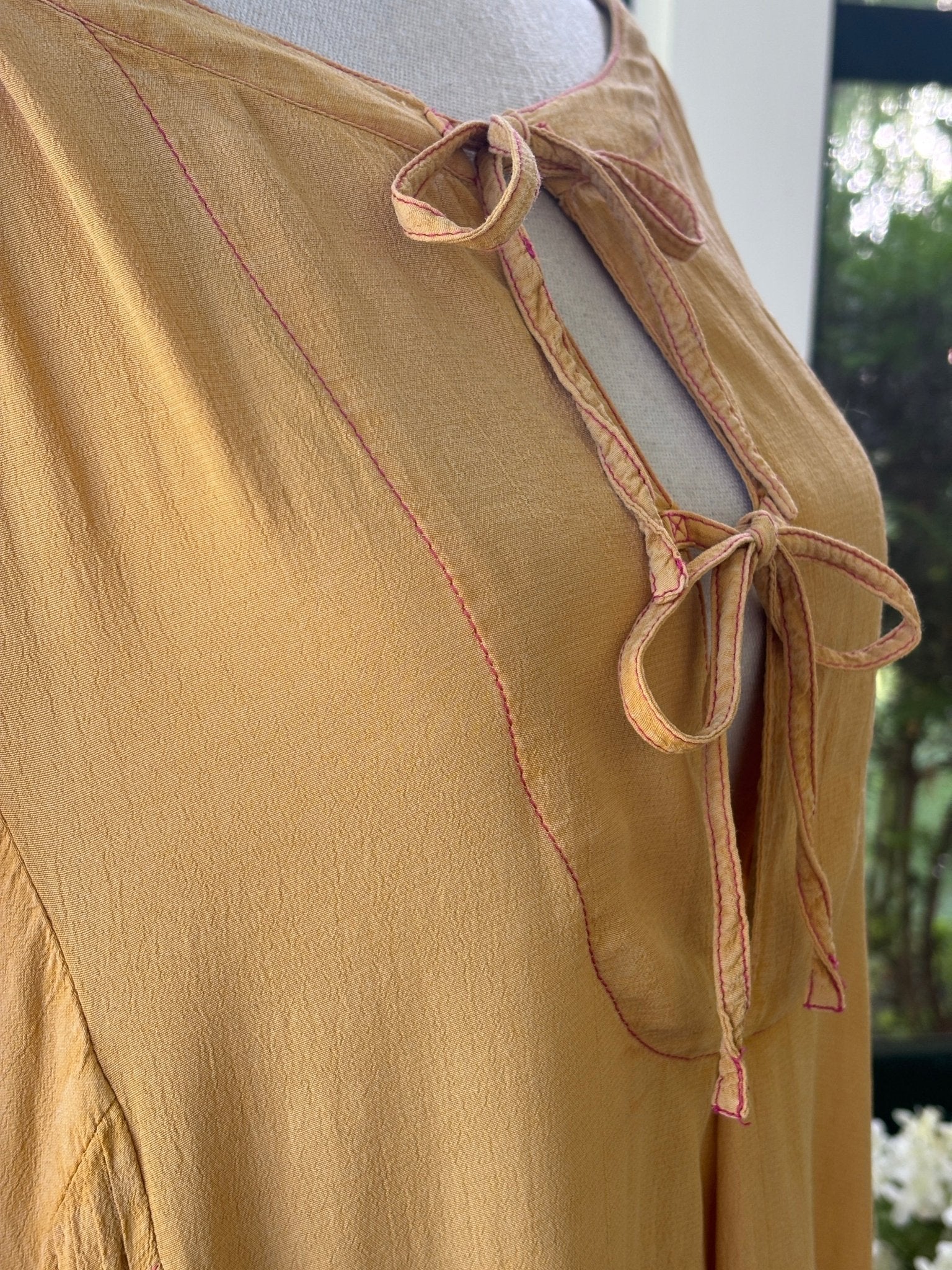 Close-up of double-tie keyhole neckline and contrast pink magenta topstitching detail