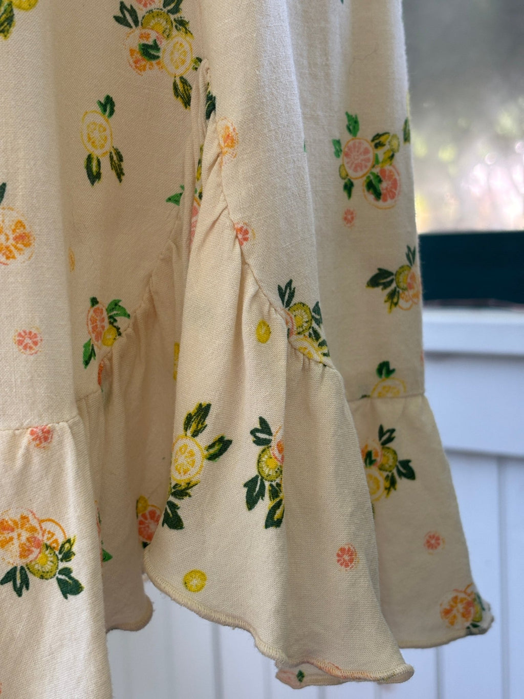 Close-up of dress side showing ruffle hem detail and citrus print fabric texture