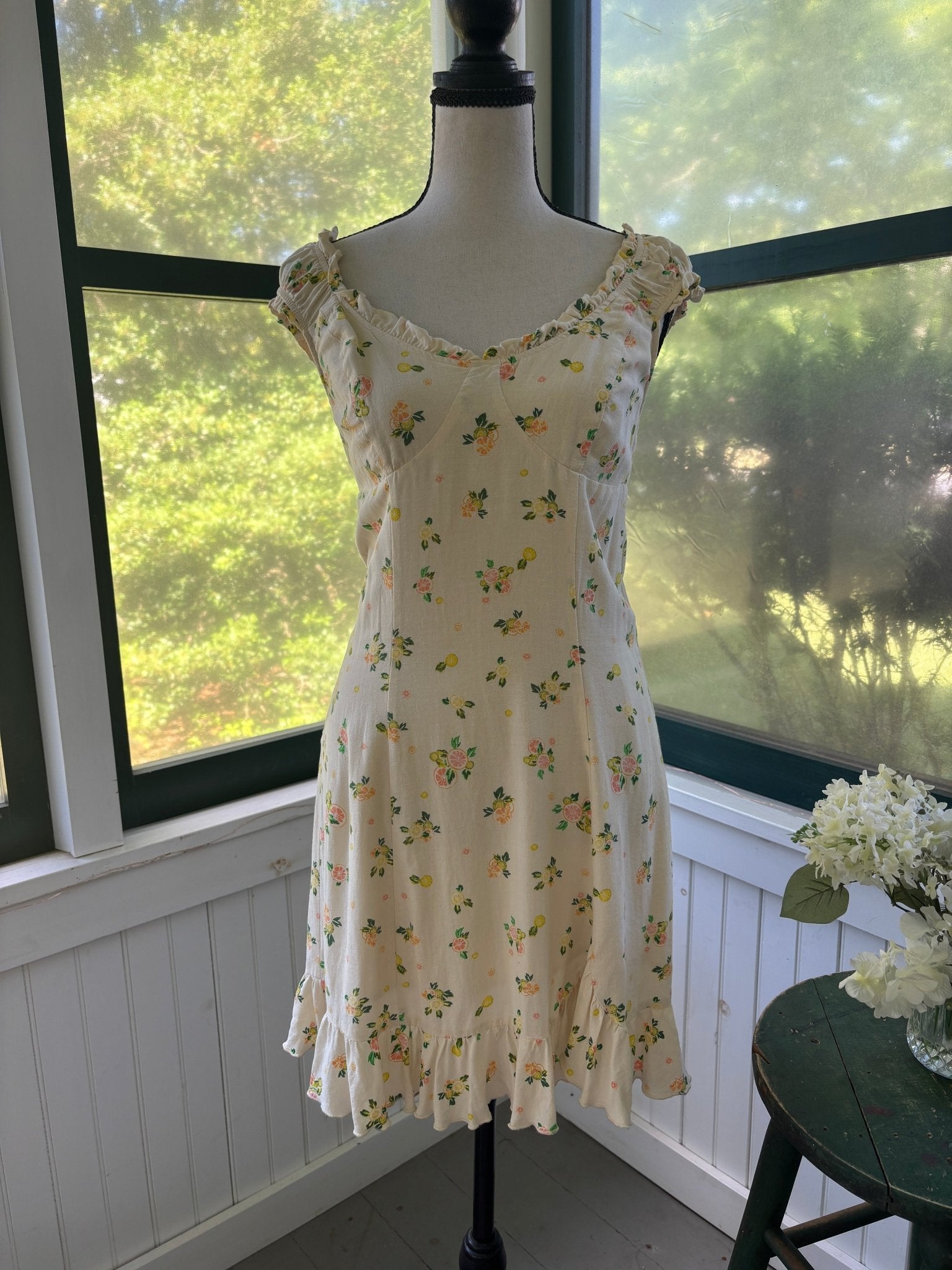 Close-up of Free People Like a Lady mini dress bodice showing ruffle cap sleeve, sweetheart neckline, and citrus lemon print on cream viscose-linen