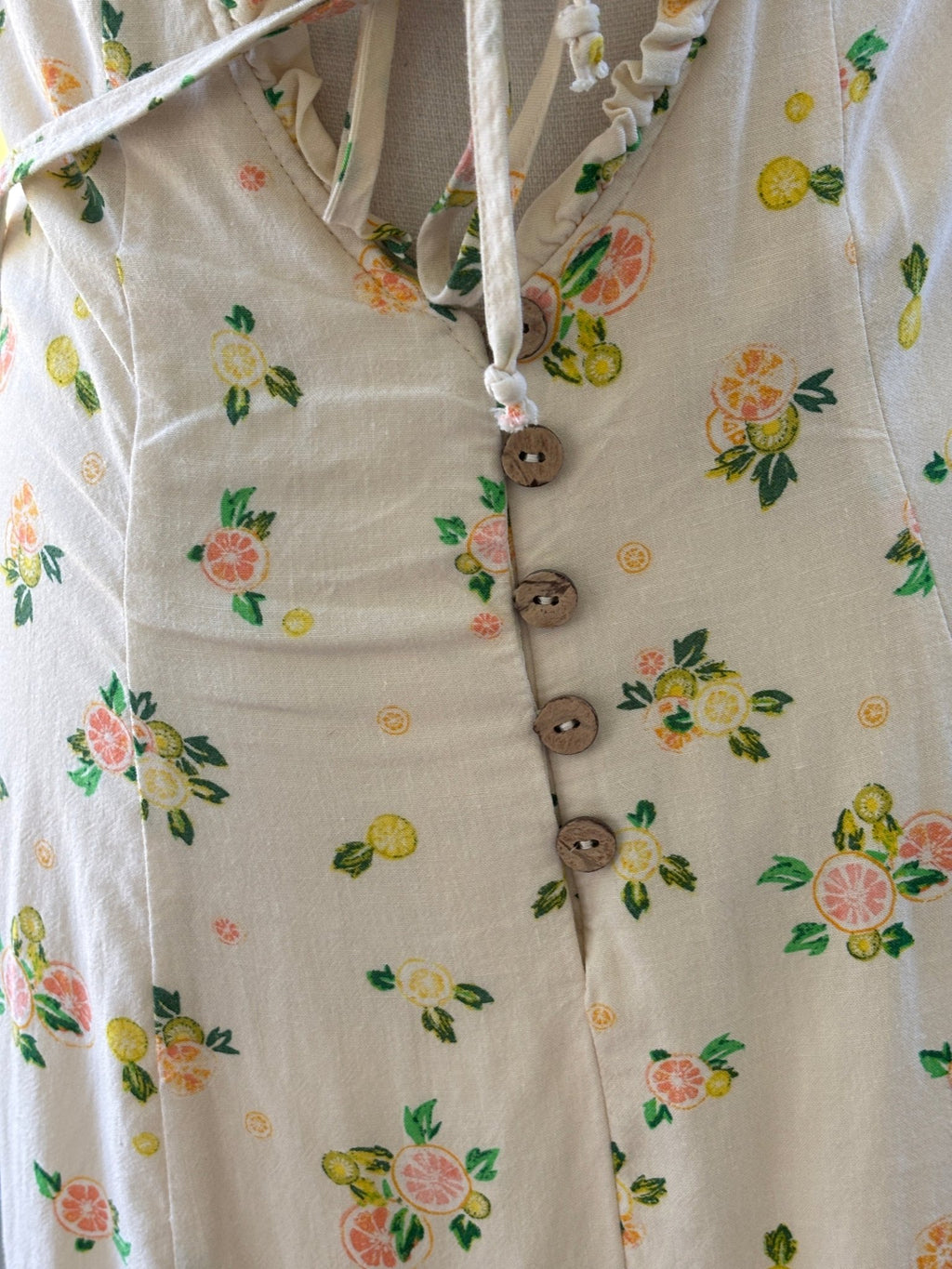 Close-up of front neckline tie bow and wooden button placket detail