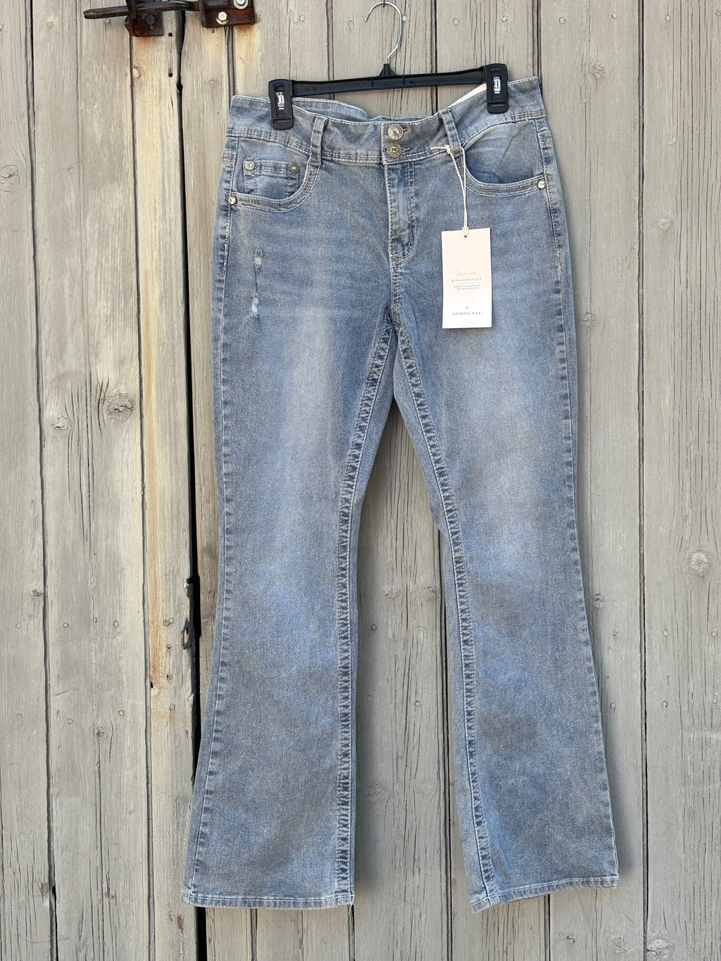 Front view of Gemma Rae mid-rise curvy bootcut jeans in light acid wash hanging on hanger, NWT tags visible