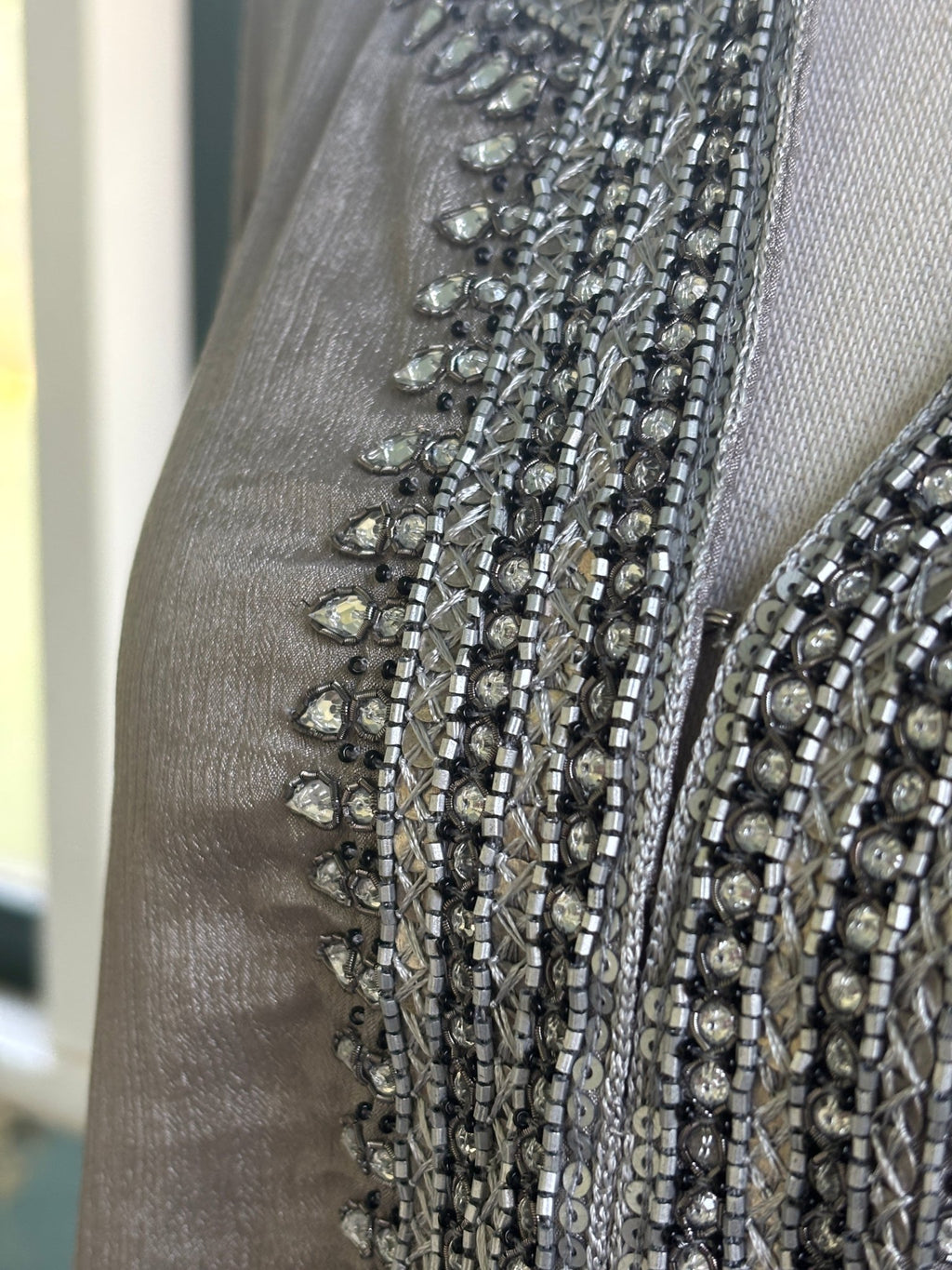 Close-up of dense rhinestone, bugle bead and silver sequin neckline embellishment on taupe silk-blend tunic dress by Grids by Sulu Collection