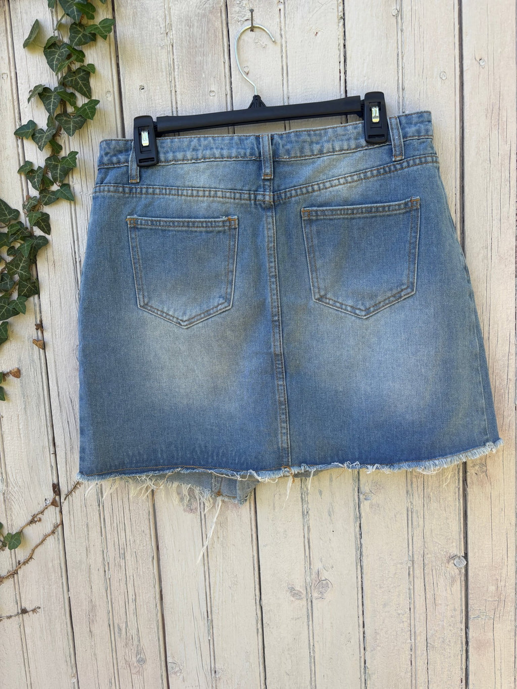 Back view of Hayden Los Angeles light wash denim wrap mini skirt showing five-pocket styling and raw frayed hem