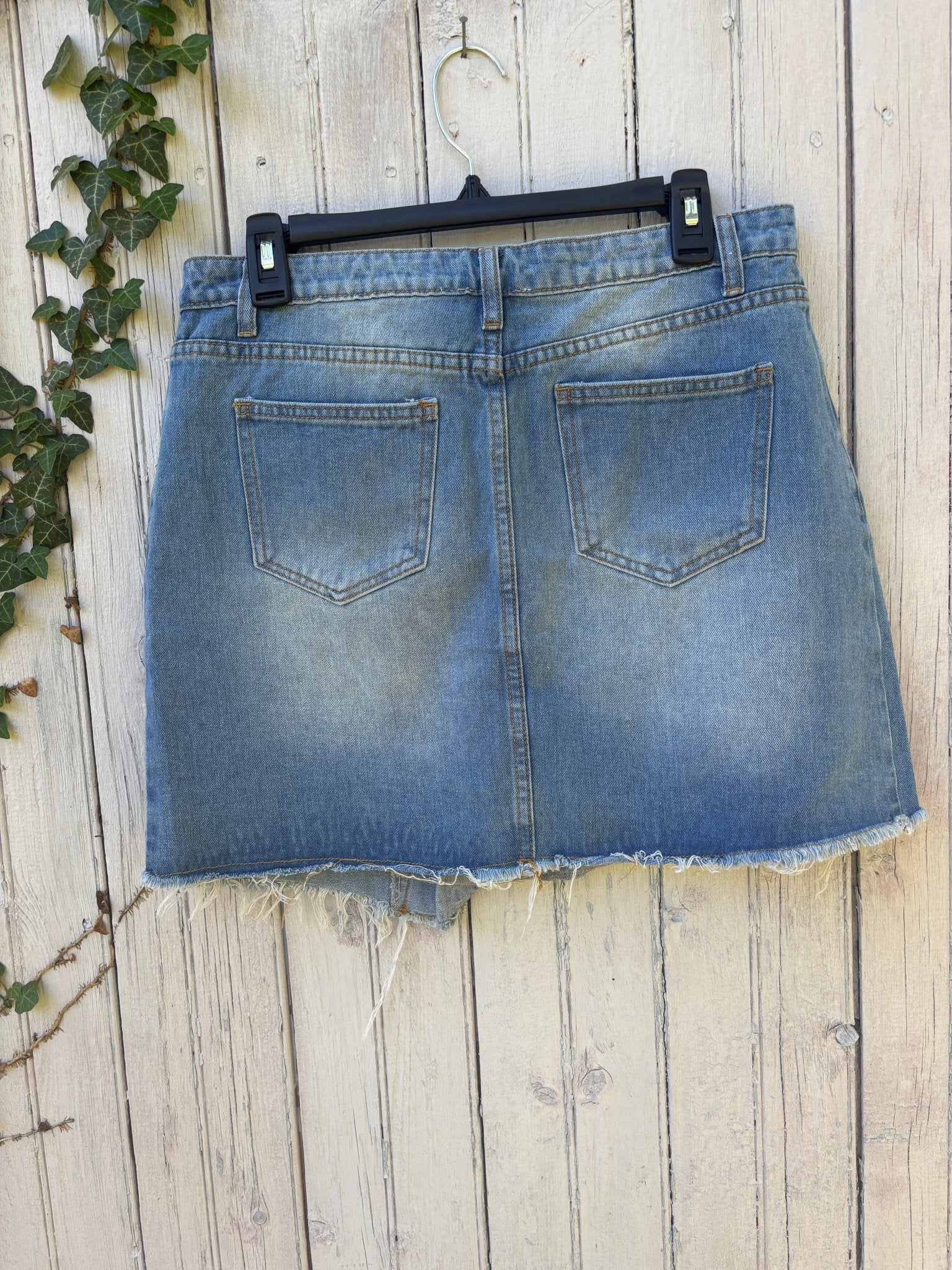 Back view of Hayden Los Angeles light wash denim wrap mini skirt showing five-pocket styling and raw frayed hem