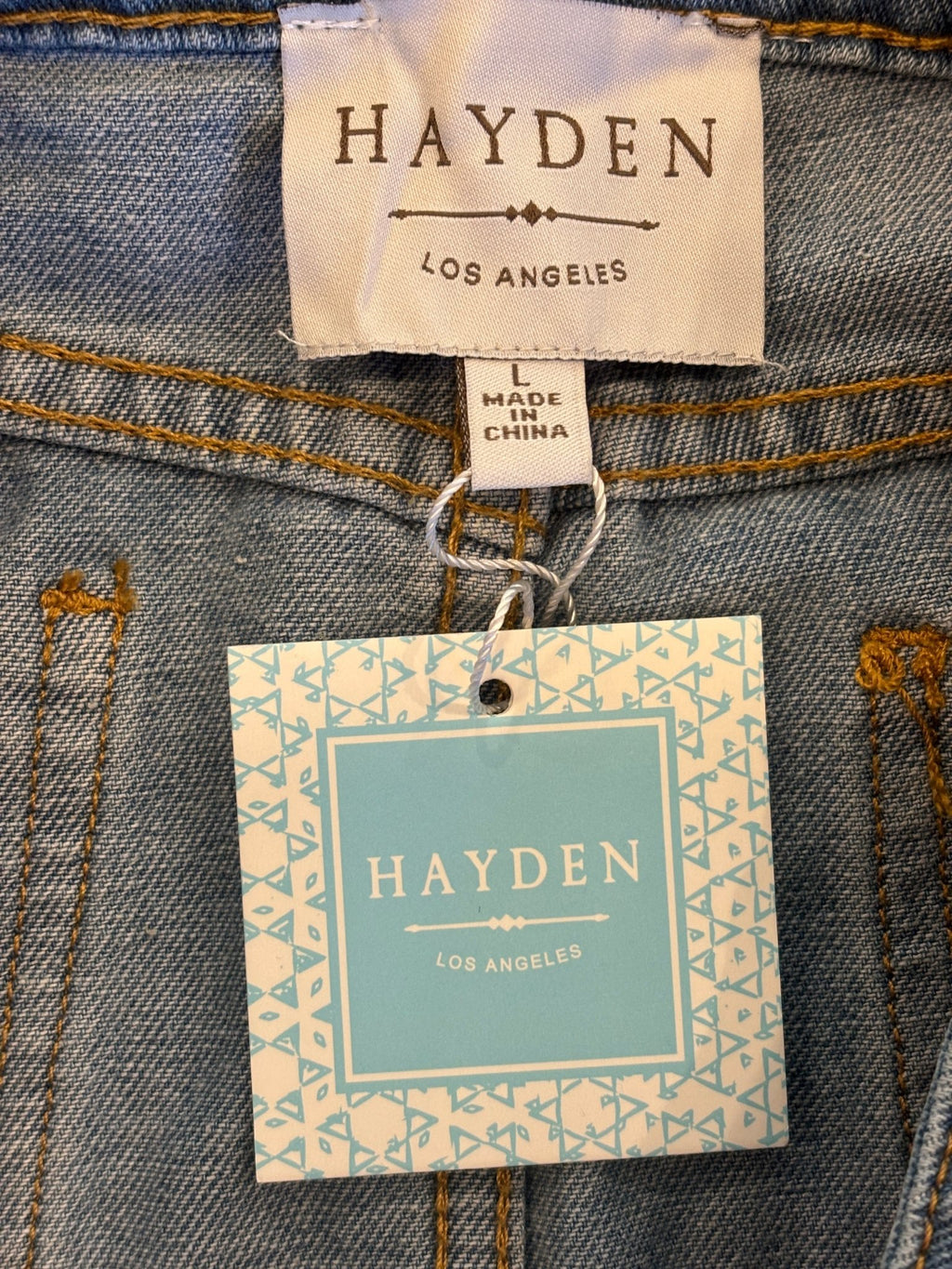Hayden Los Angeles brand label with NWT hang tag and size Large on light wash denim wrap mini skirt