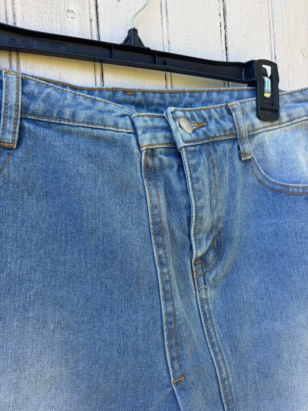 Close-up of faux-wrap front, antique brass hardware and high waist detail on Hayden LA light wash denim mini skirt