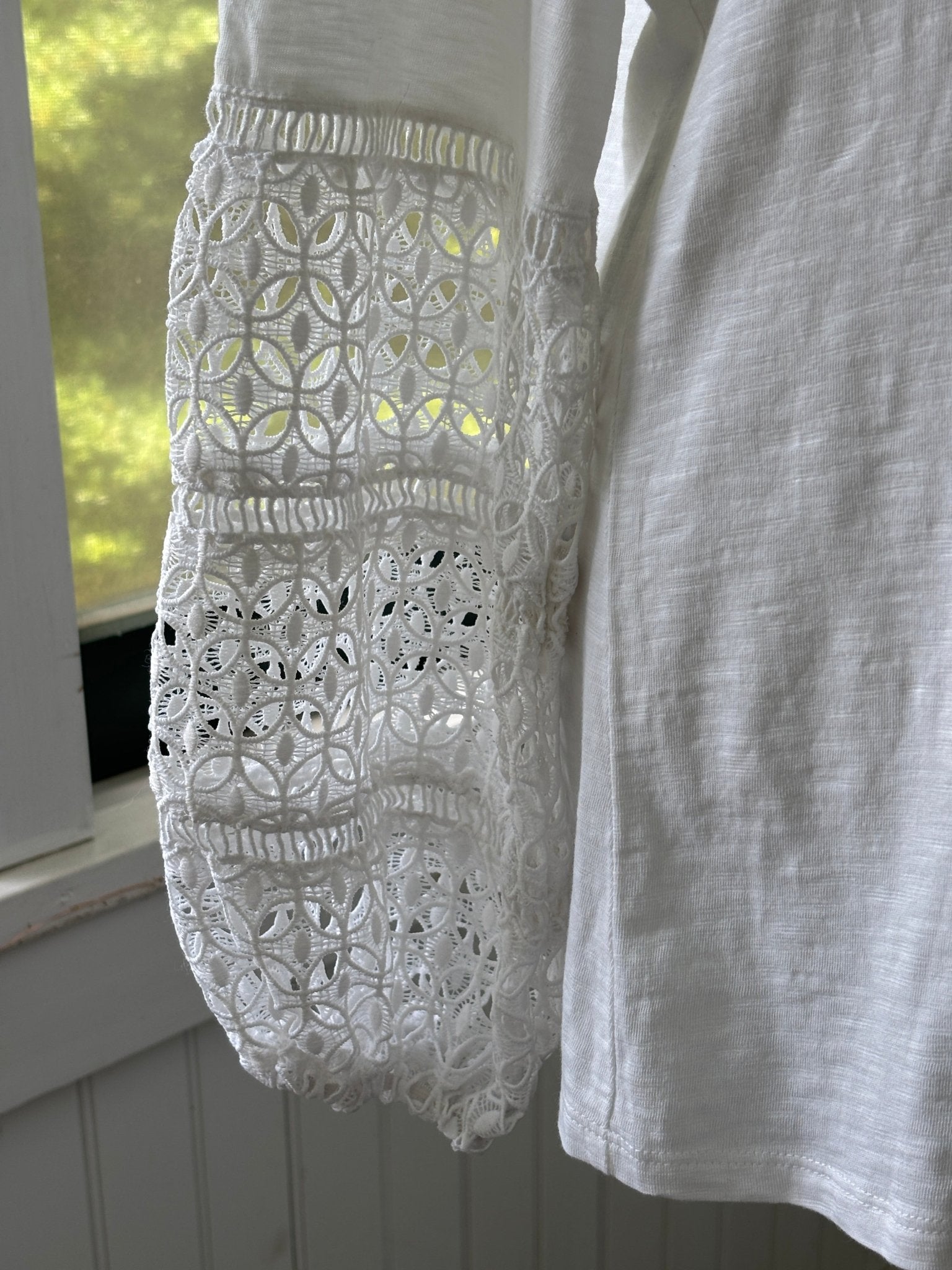 Close-up of floral open stitch crochet lace bell sleeve detail on JM Collection white top