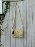 Kaleidoscope Accessories natural ivory crochet crossbody bag hanging on weathered fence, braided strap and tassel zipper pull, NWT