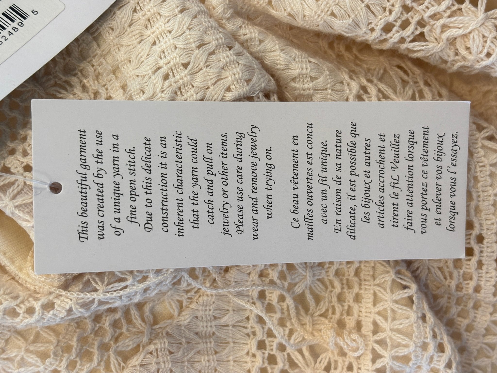 Hang tag back showing care note about delicate open stitch yarn construction