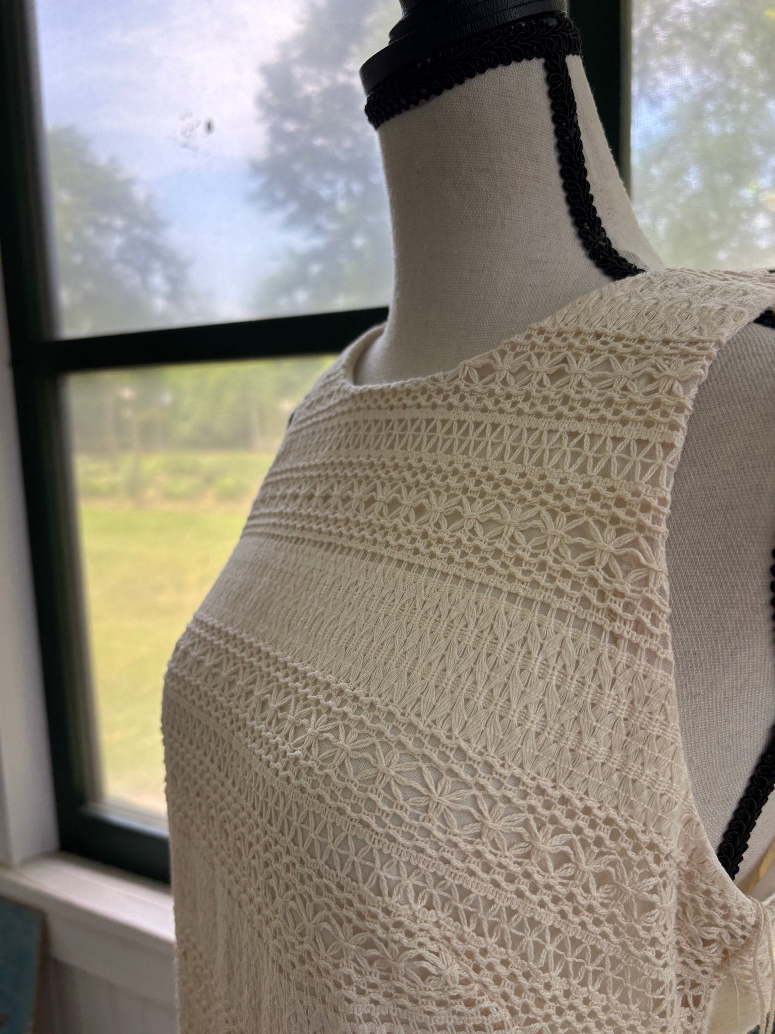 Close-up of fringe hem detail on London Times natural crochet maxi dress