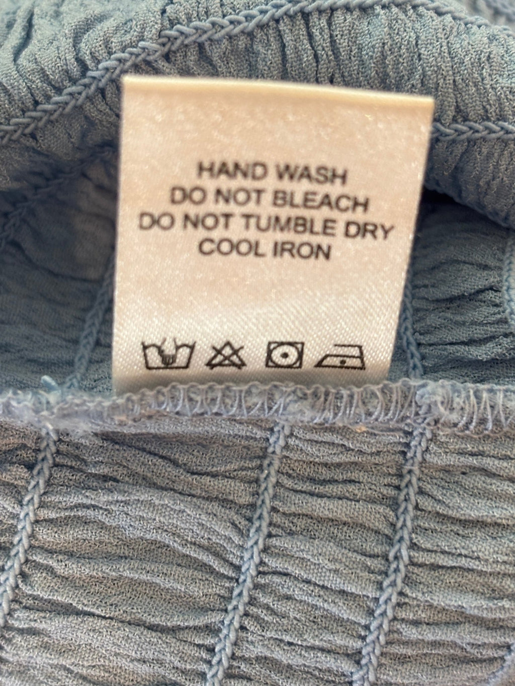 Care label for Lovers + Friends smocked mini skirt, hand wash instruction