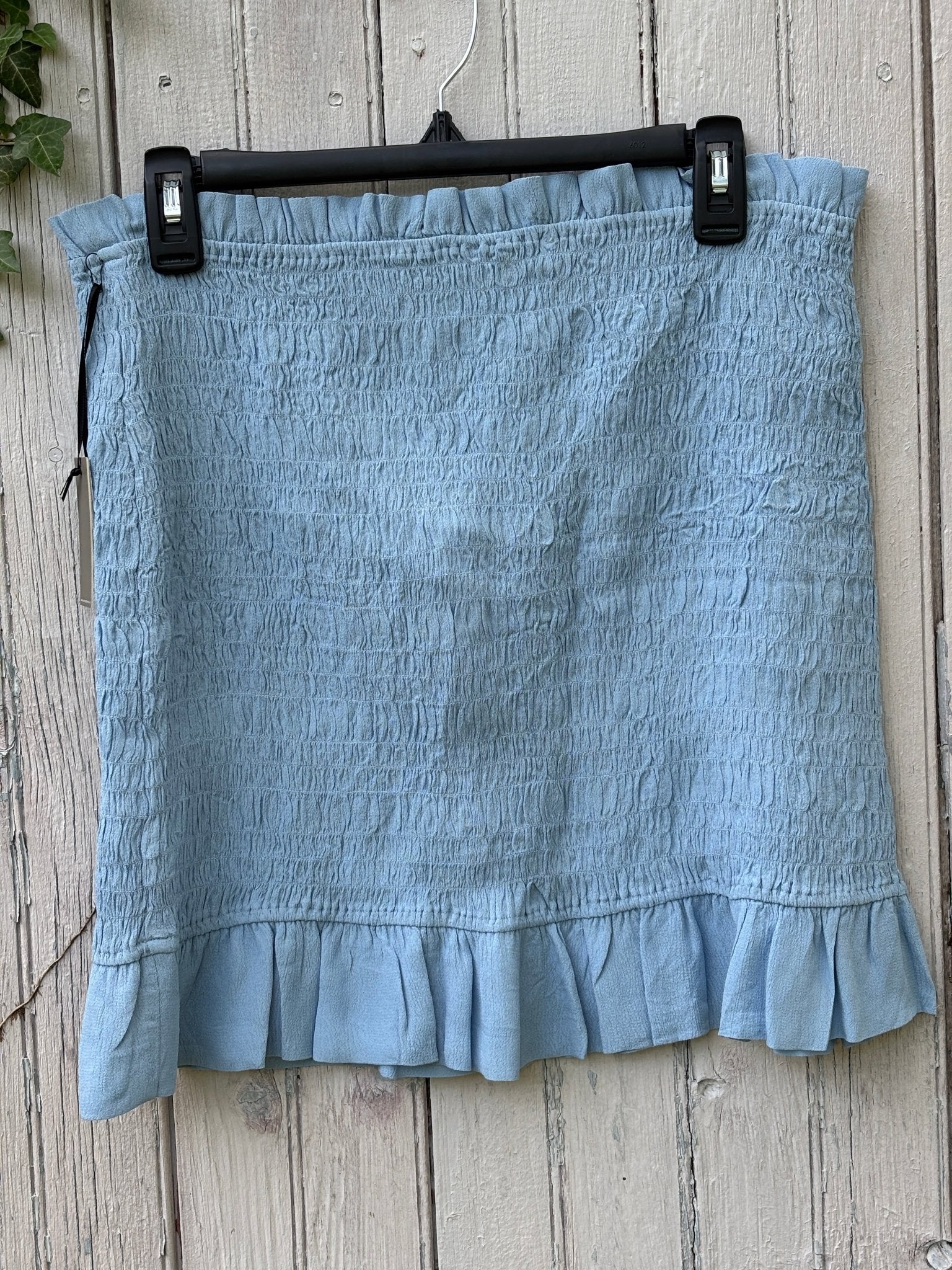 Lovers + Friends sky blue smocked mini skirt with ruffle hem, front view on hanger