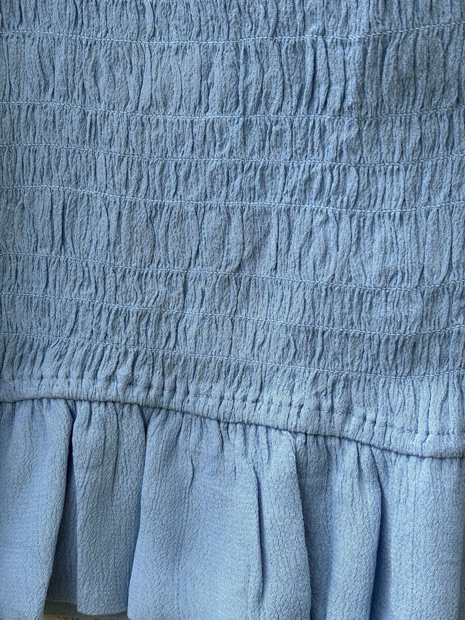 Close-up of allover smocking texture on Lovers + Friends blue mini skirt