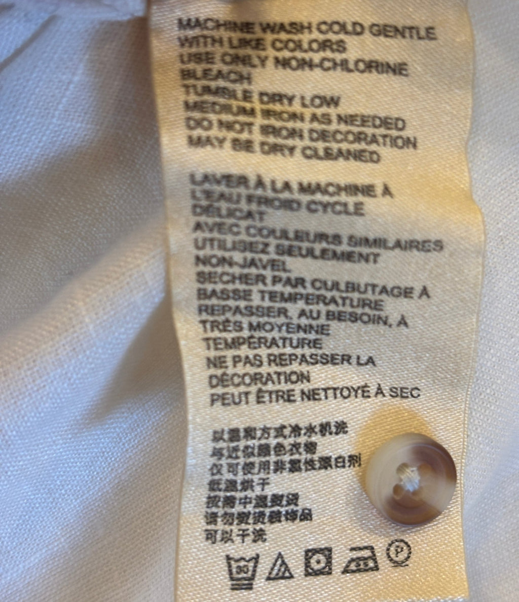 Care label showing machine wash cold gentle for Maeve by Anthropologie ivory linen lace-up top