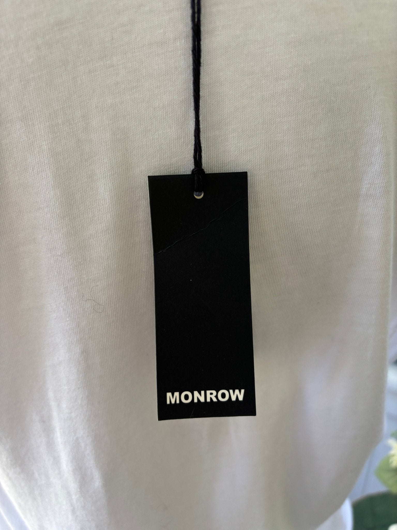 Close-up of Monrow original black hang tag on white dress