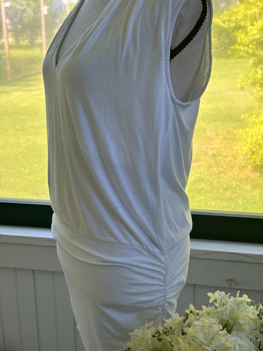 Side view of Monrow white mini dress on mannequin showing ruched silhouette and sleeveless cut