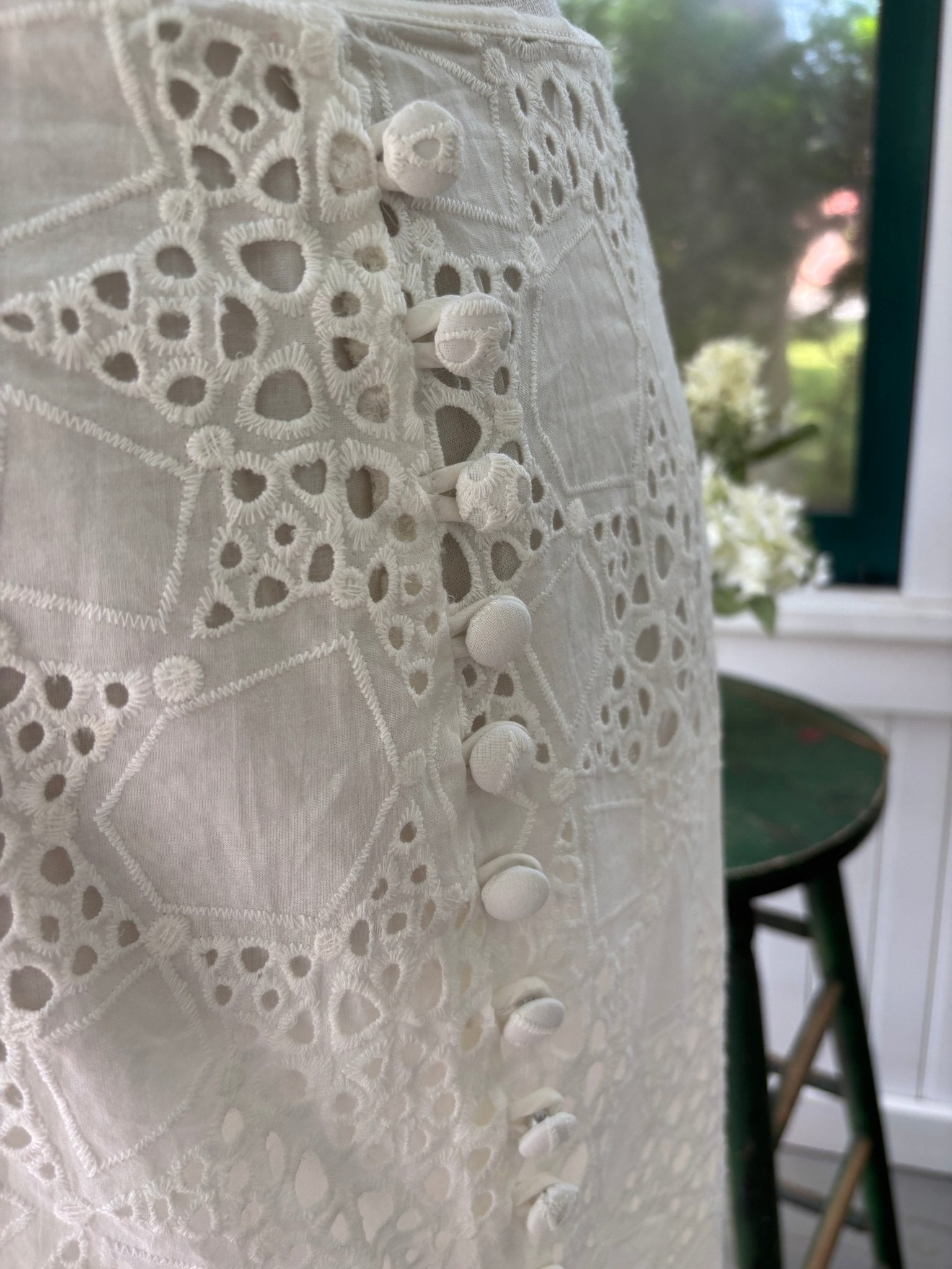 Close-up of covered button detail and crochet-cut eyelet pattern on Sabo Luxe white midi skirt