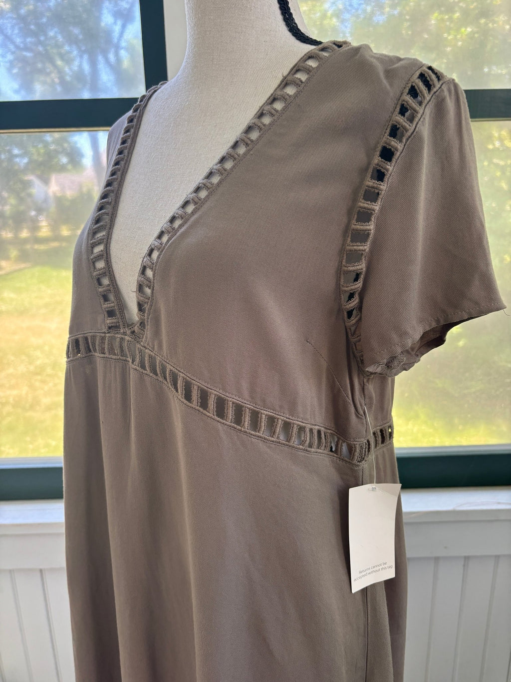 Close-up of ladder-stitch cutout trim at V-neckline and empire seam on Tobi taupe mini dress