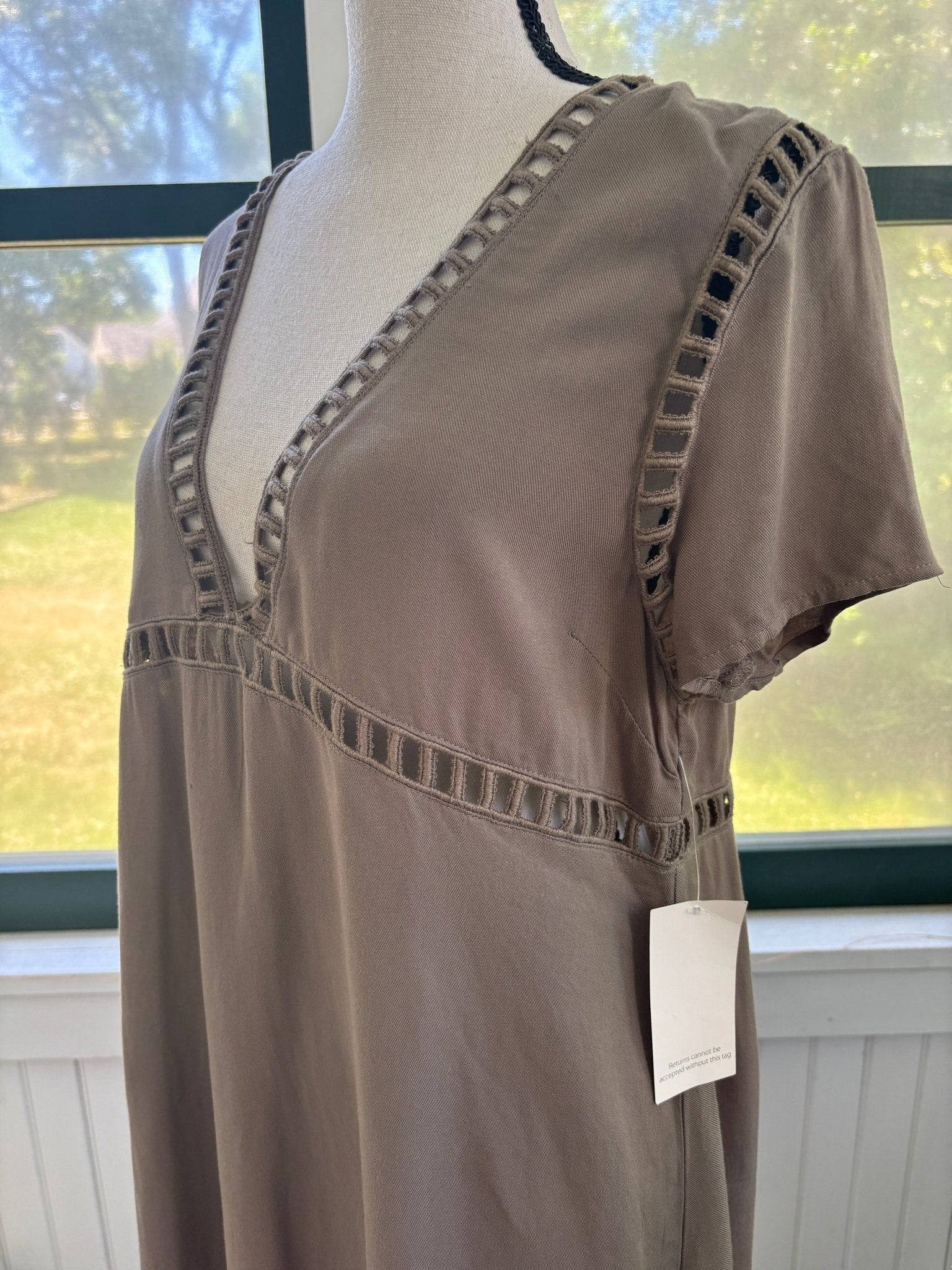 Close-up of ladder-stitch cutout trim at V-neckline and empire seam on Tobi taupe mini dress