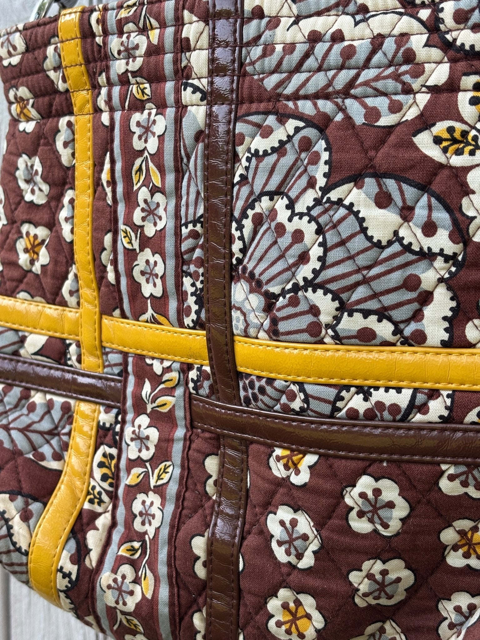 Close-up of mixed print patchwork panels with mustard yellow patent leather trim detail on Vera Bradley brown floral shoulder bag