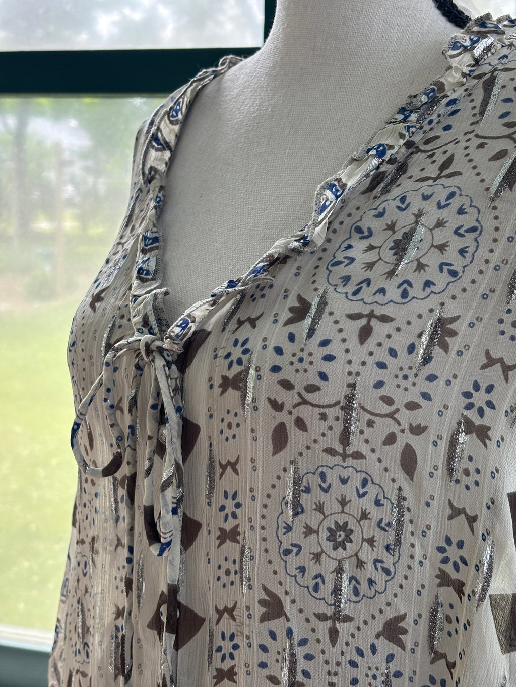 Close-up of ruffled V-neckline and self-tie closure on Zara ivory block print blouse